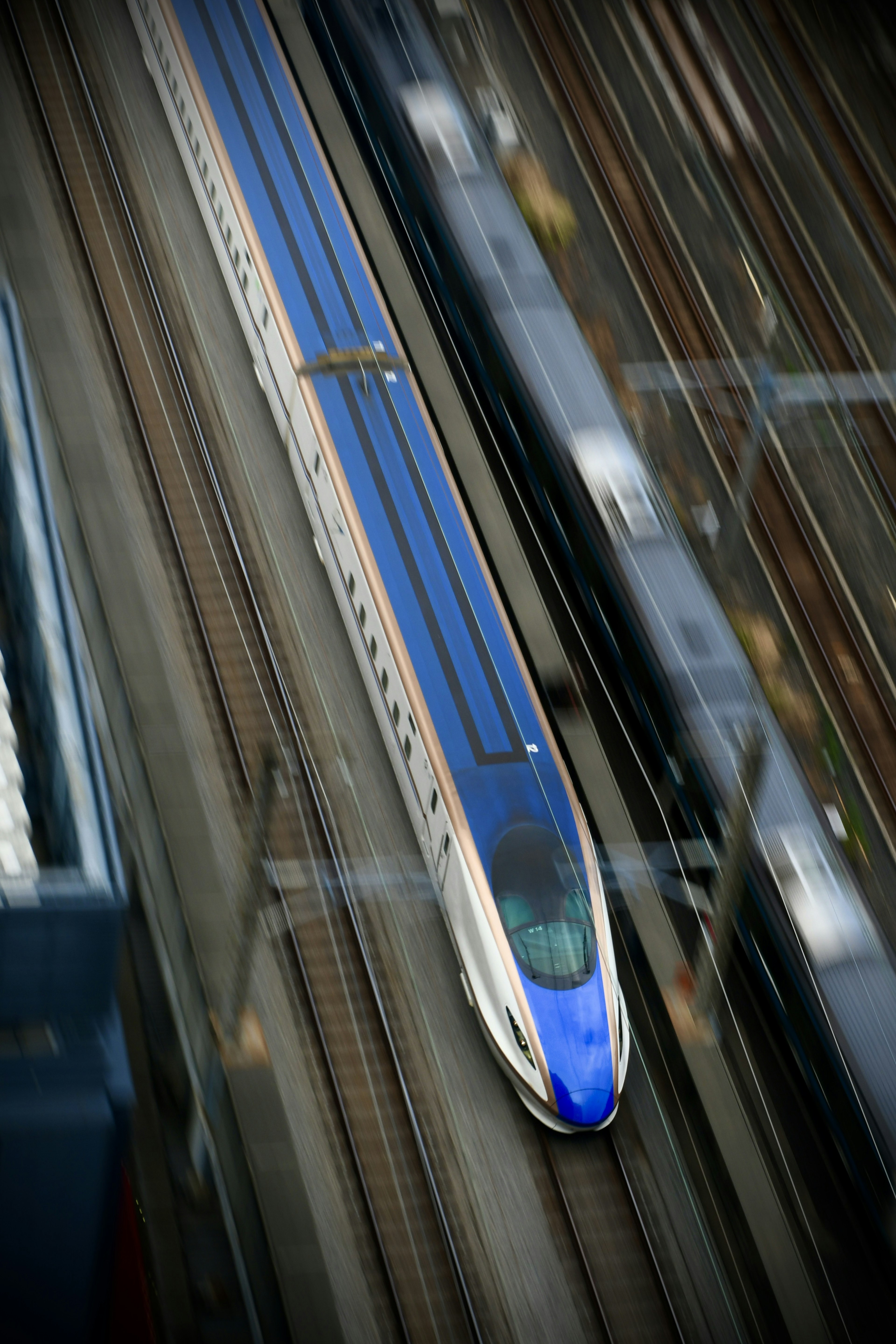 Un treno Shinkansen blu che si muove su binari visto dall'alto