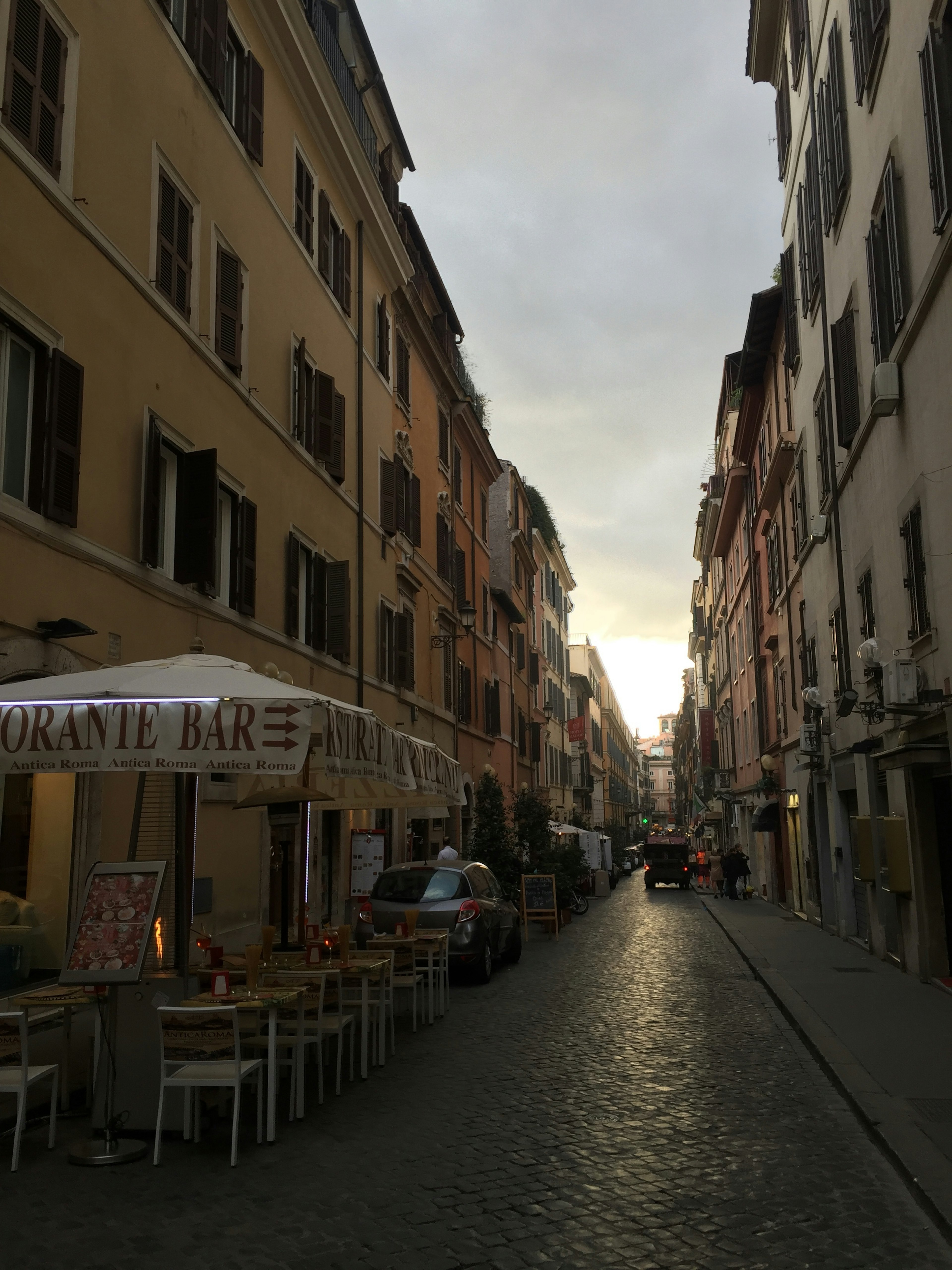 Escena de calle tranquila en Roma con cafés y restaurantes a lo largo de un camino de adoquines