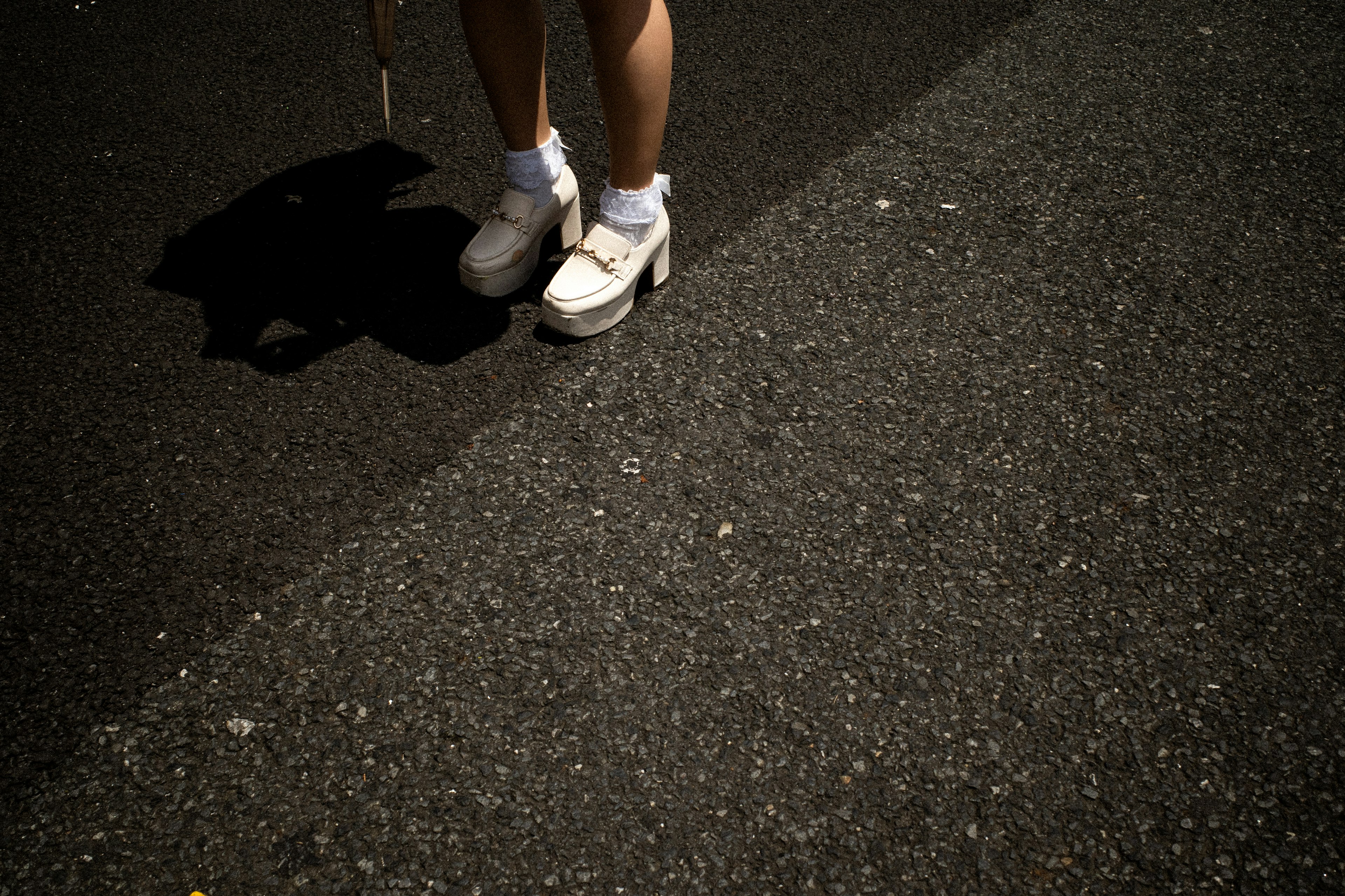 Pies en zapatos blancos sobre asfalto