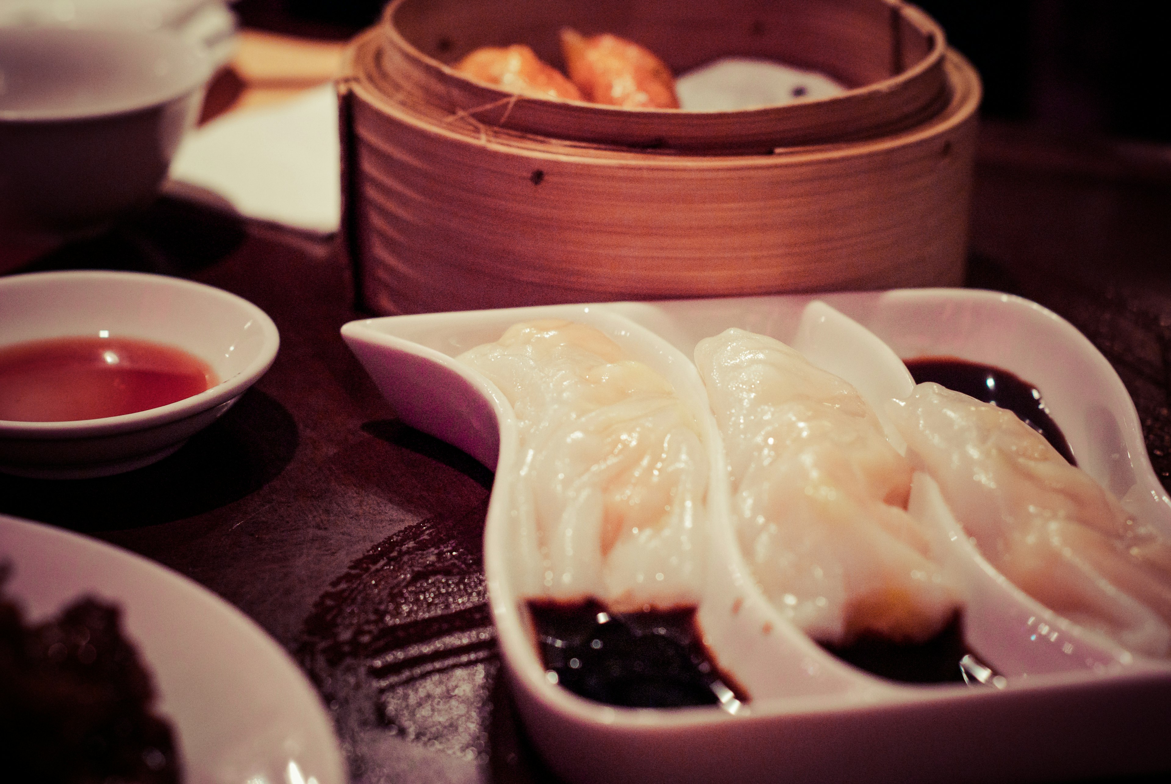 Deliciosos dim sum servidos en un plato con una vaporera al fondo