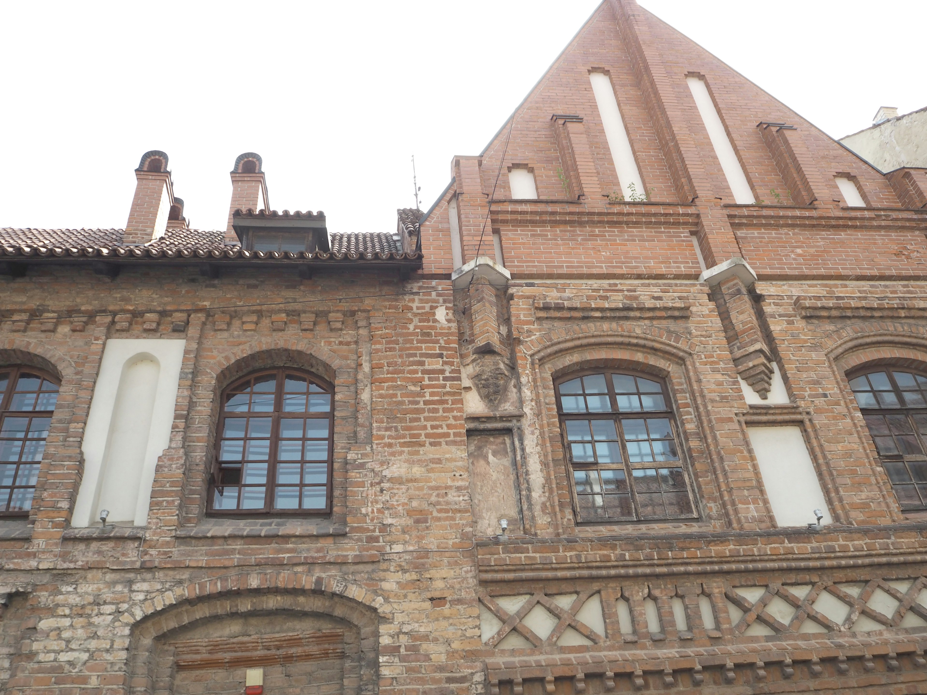 Façade d'un bâtiment en briques historiques avec fenêtres et éléments décoratifs