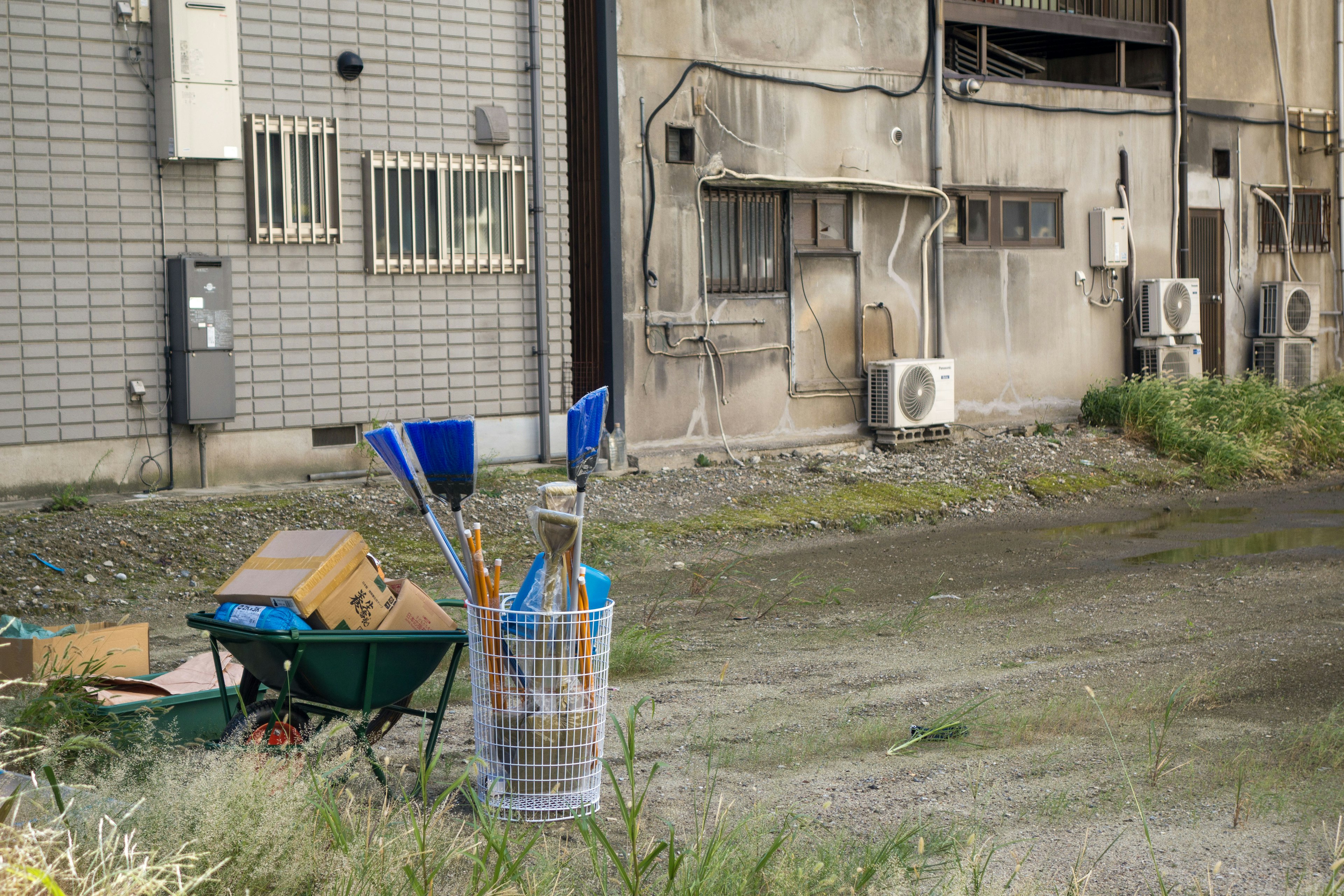 Scene with a wheelbarrow and cleaning tools next to an old building