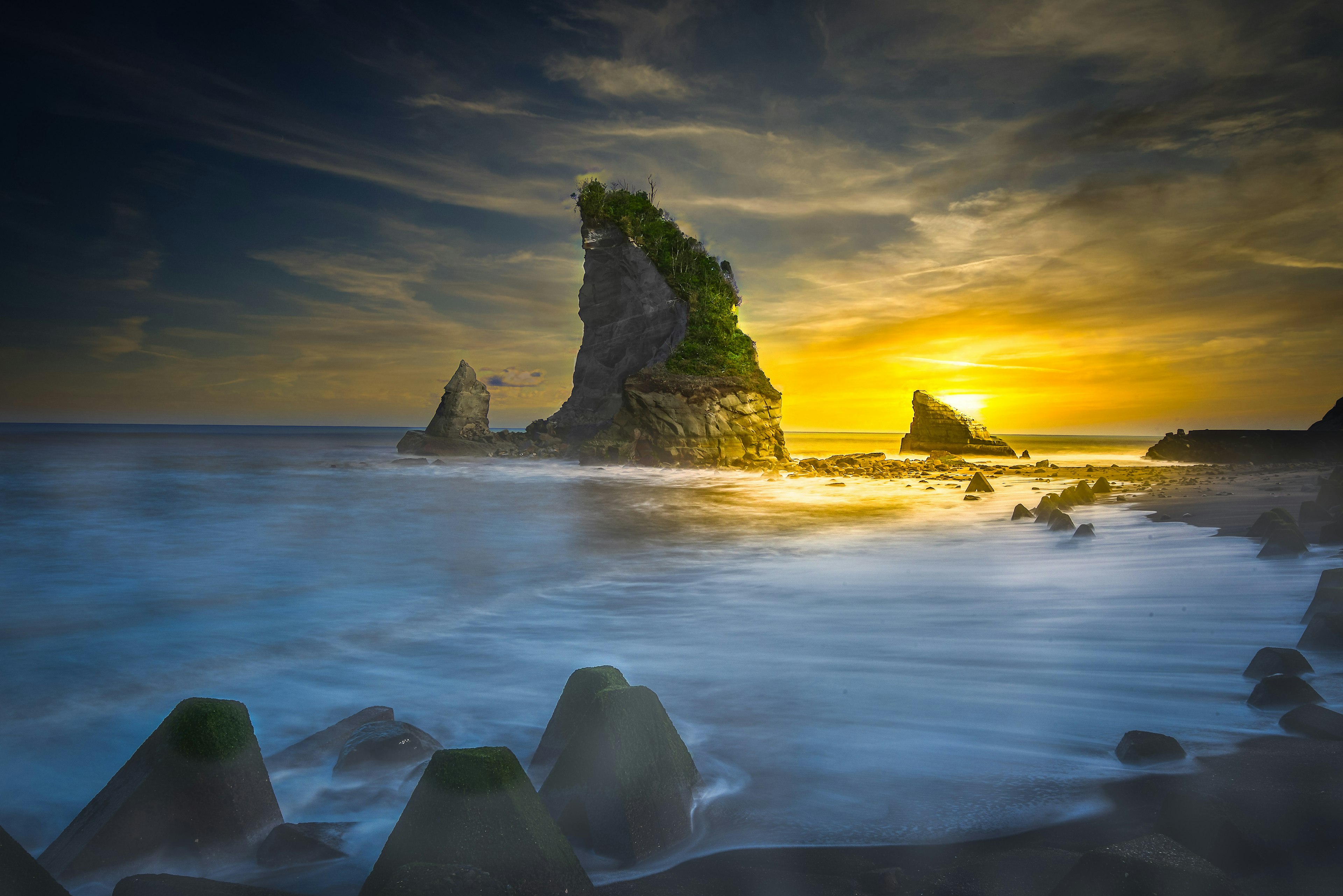 Vista panoramica di una formazione rocciosa verde al tramonto sull'oceano