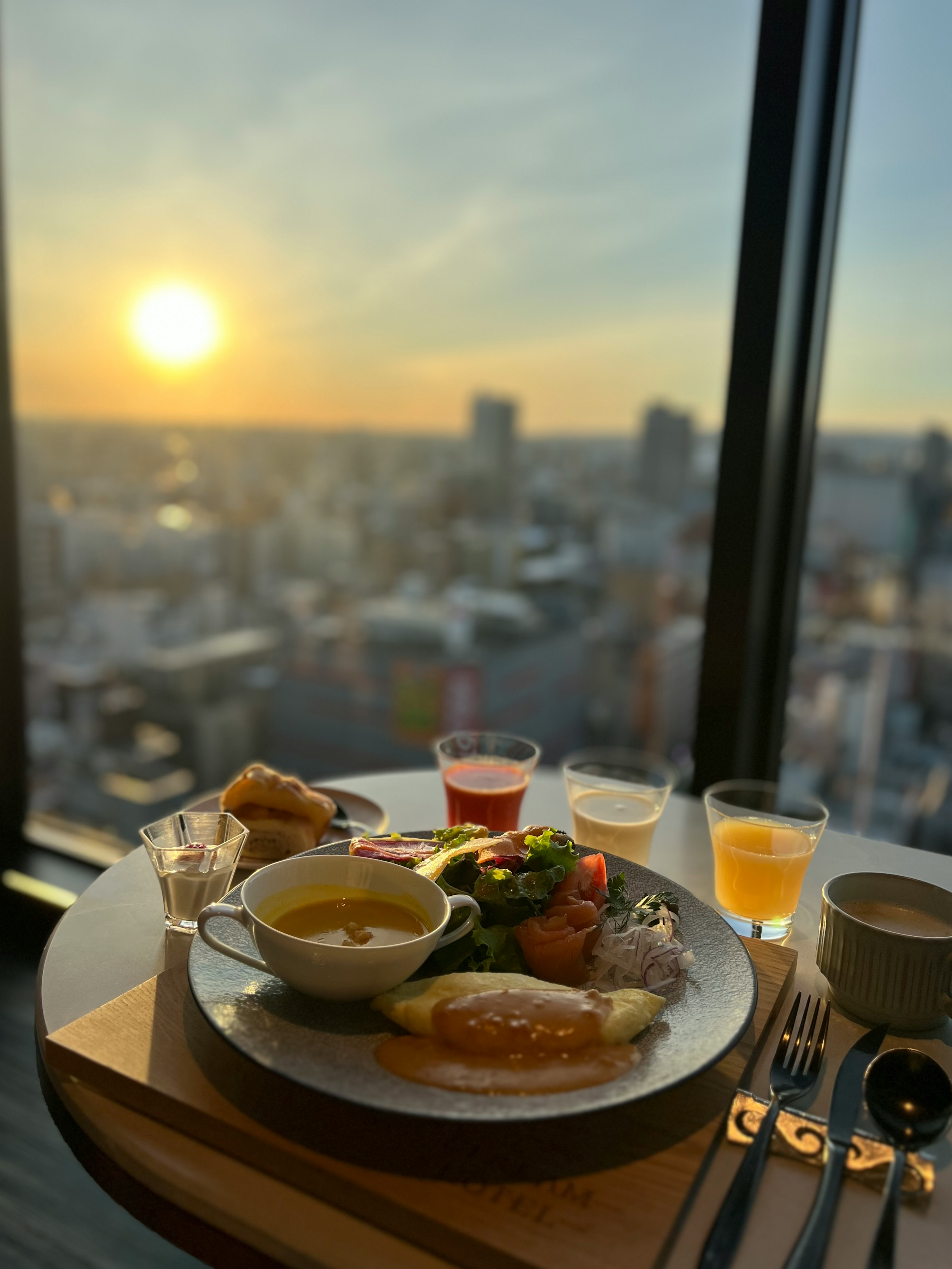 Assiette de petit-déjeuner avec des boissons devant un magnifique lever de soleil