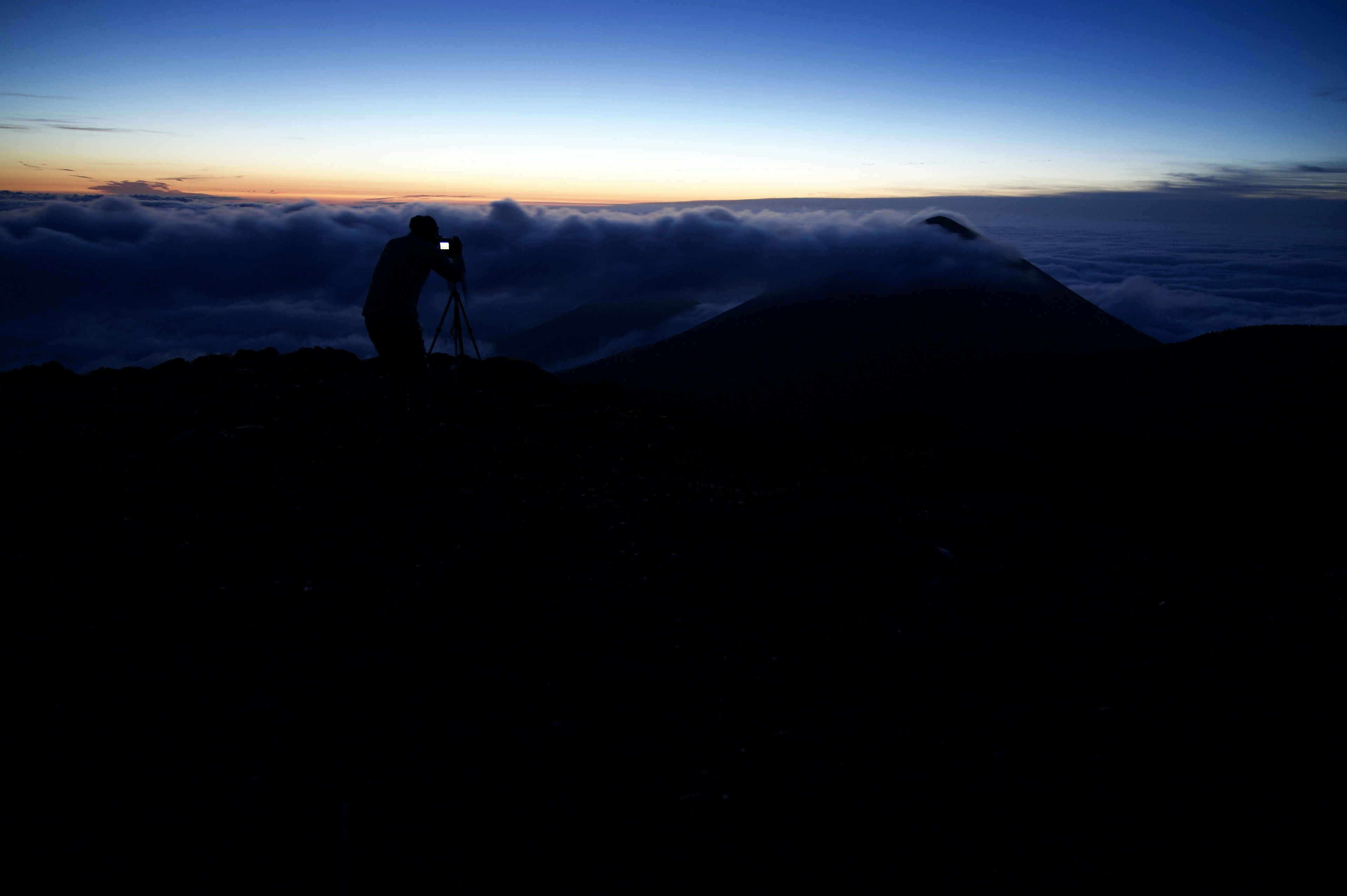 Personne avec un appareil photo au sommet d'une montagne au lever du soleil