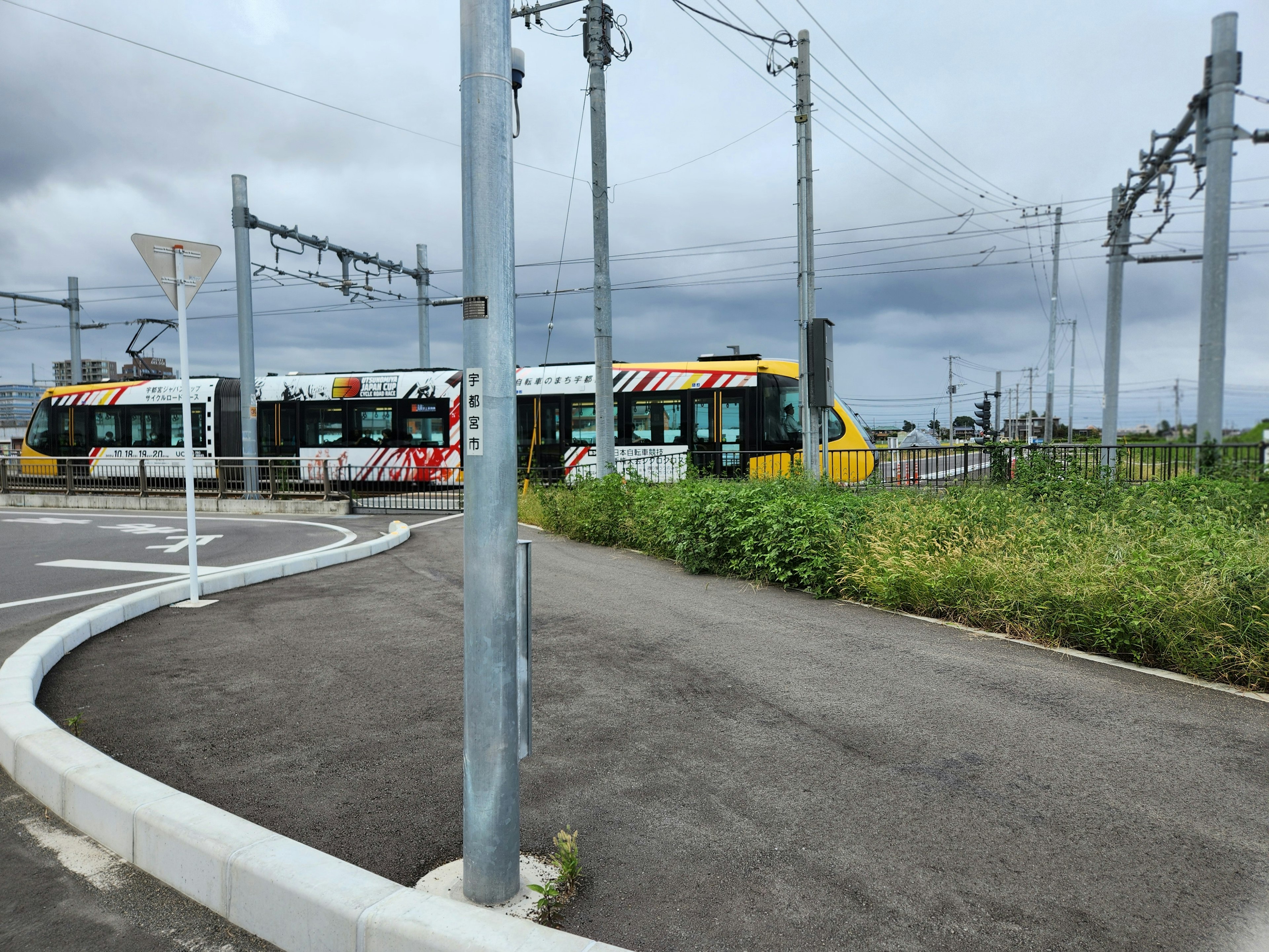 Straßenbahn an einer Kreuzung mit Oberleitungen und bewölktem Himmel