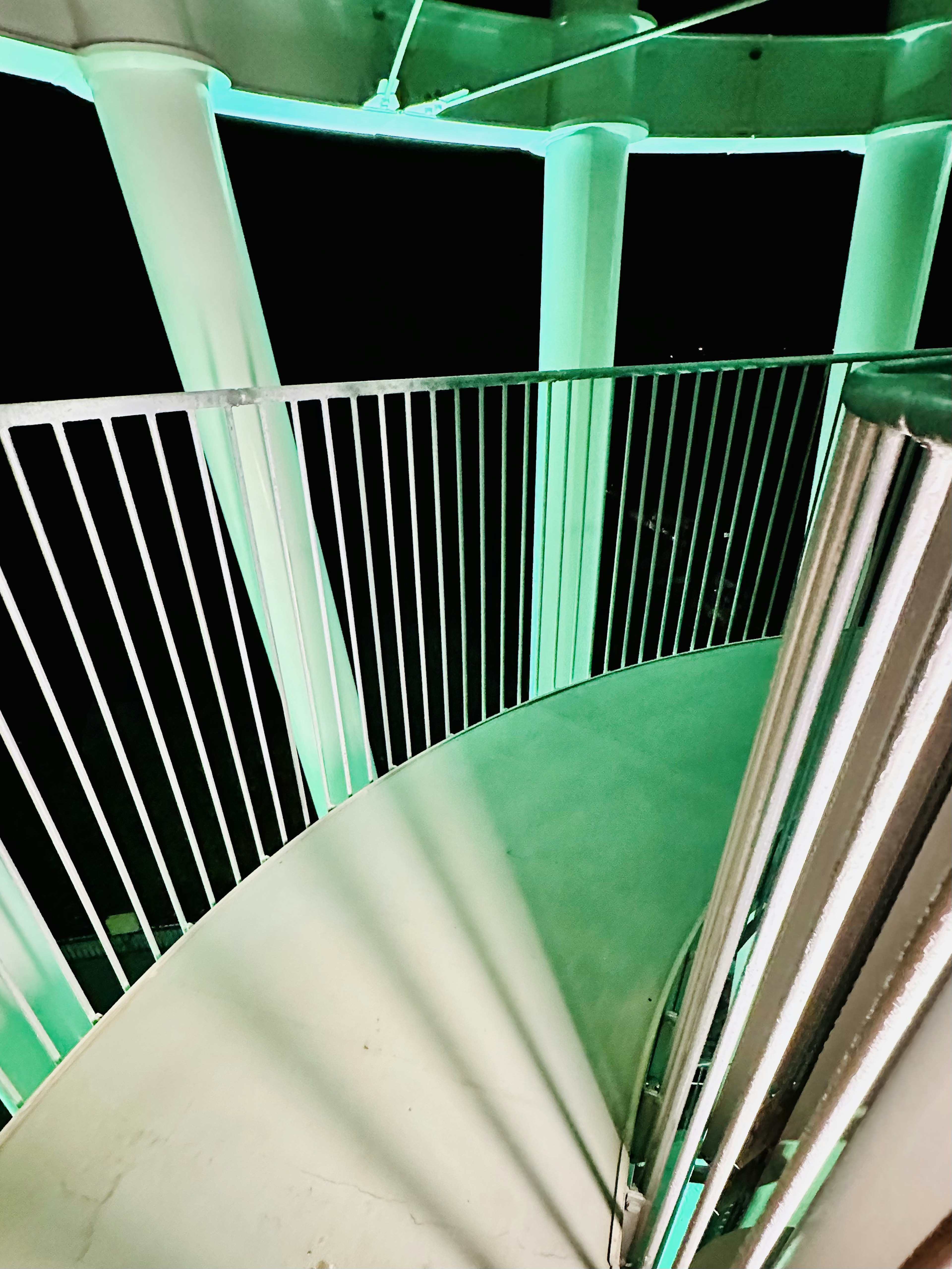 View from above a spiral staircase illuminated with green lighting