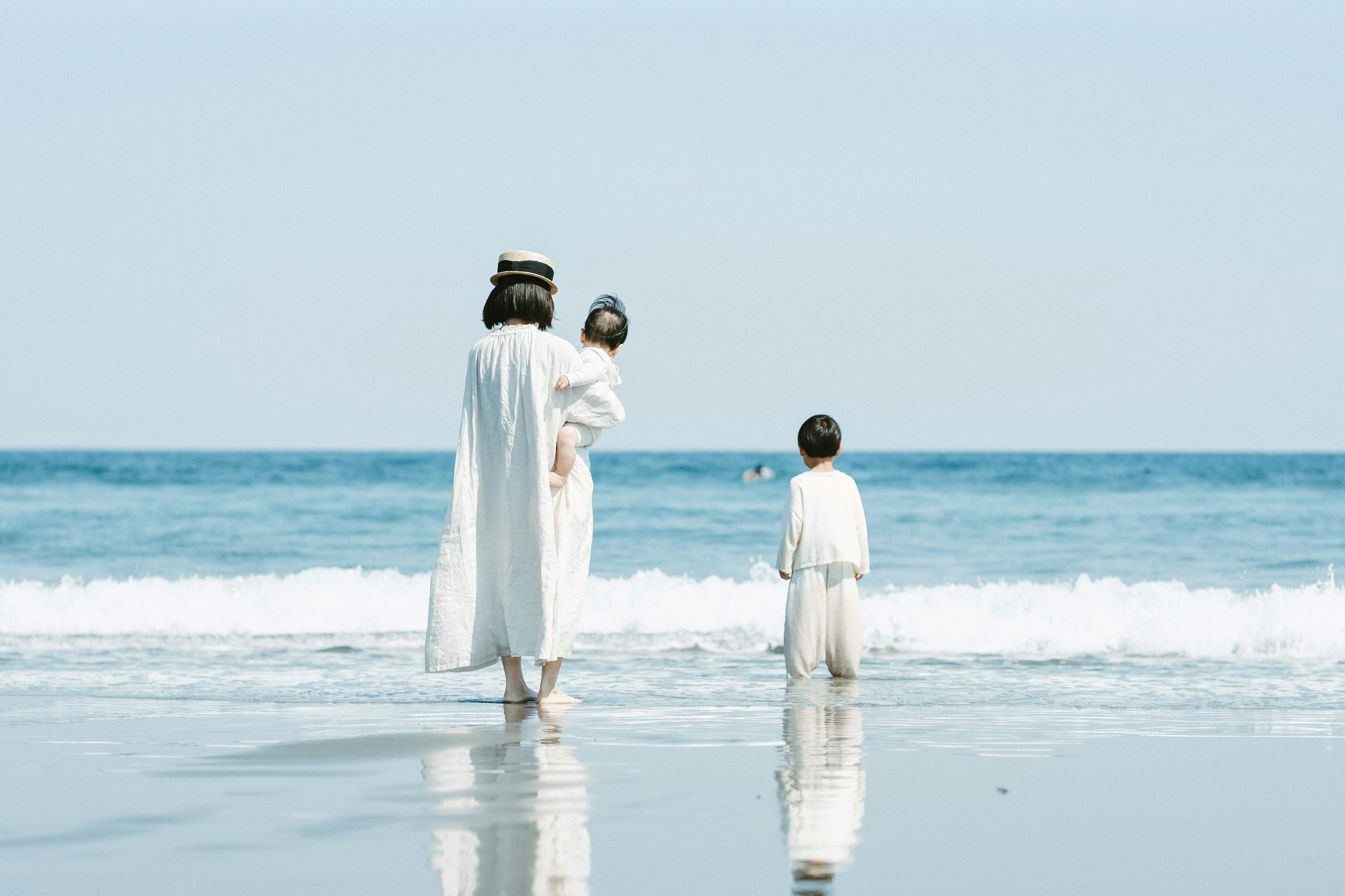 Scena di una madre e bambini in abiti bianchi che giocano sulla spiaggia