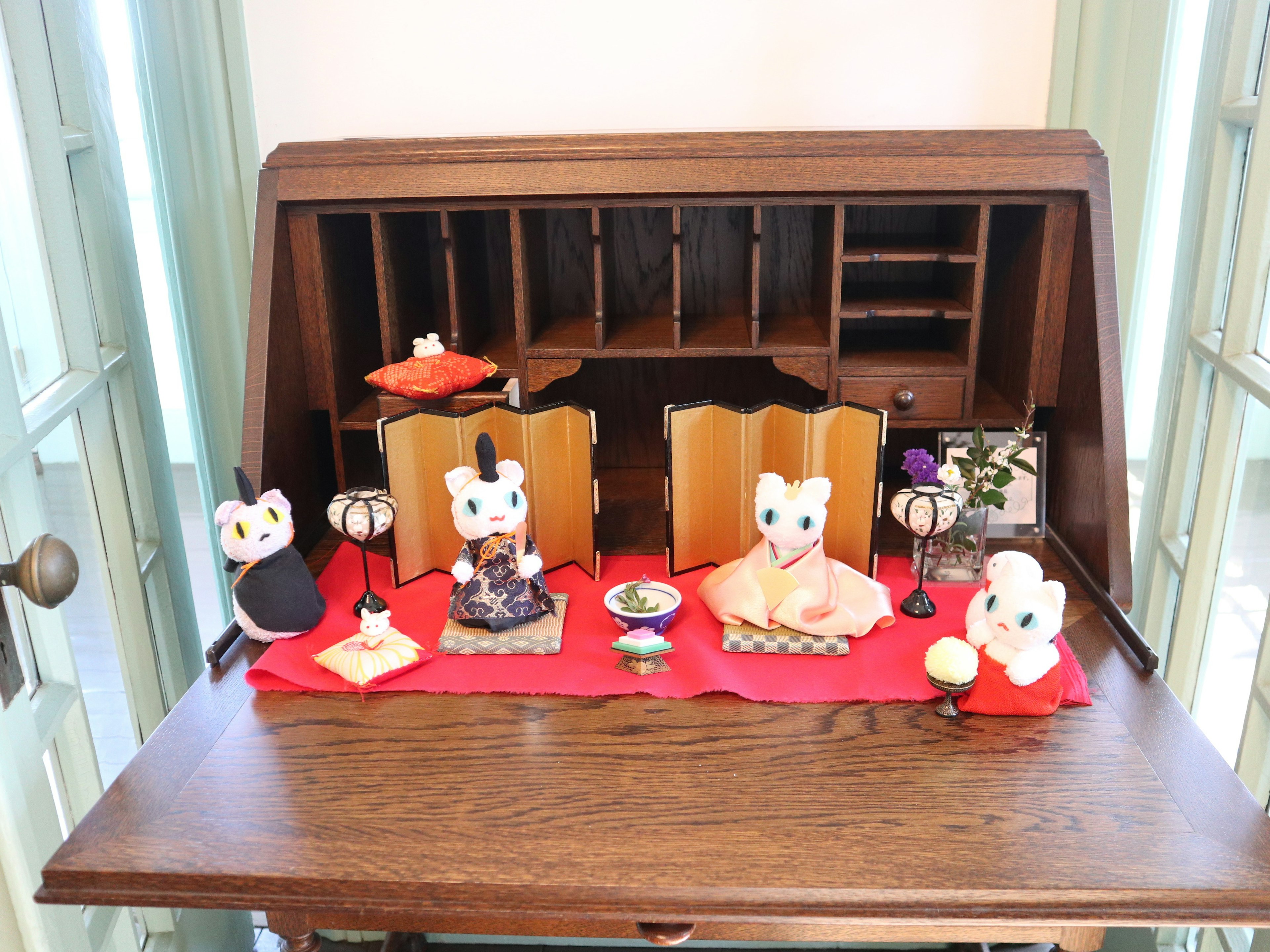 Wooden desk displaying cute cat figurines and traditional ornaments