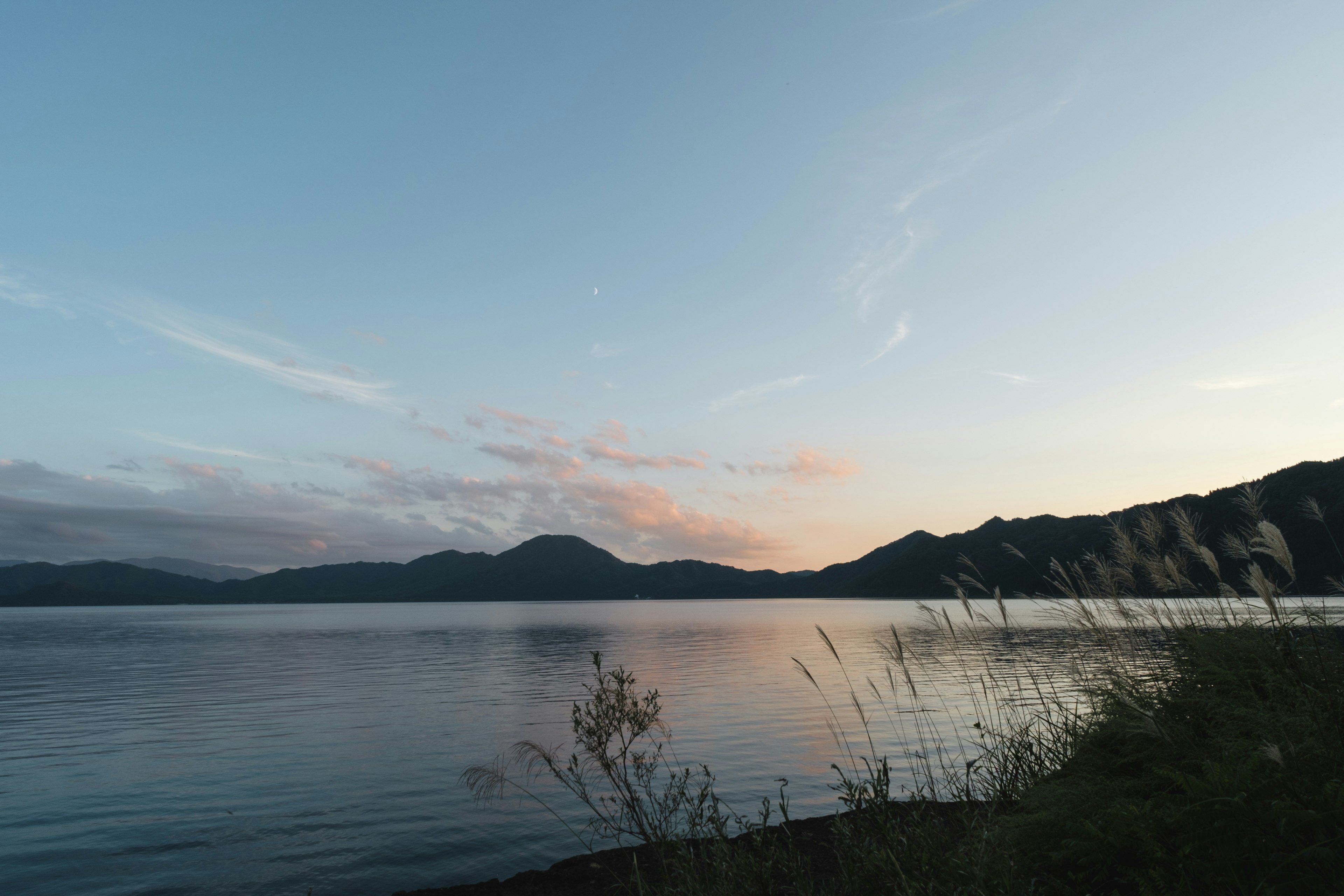 Serene lake view with mountain silhouettes and soft evening light