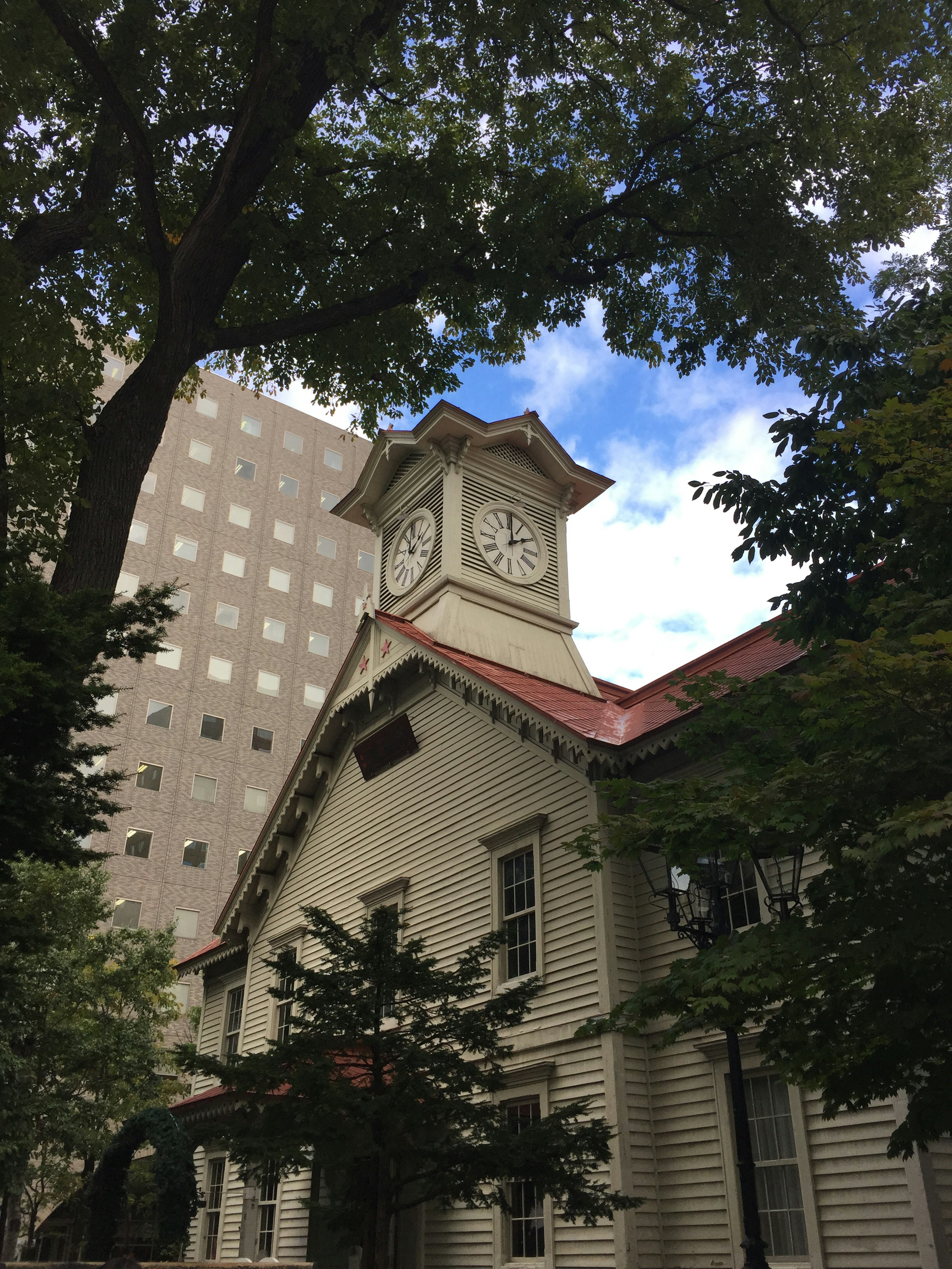 Historisches Gebäude mit Uhrturm umgeben von modernen Wolkenkratzern