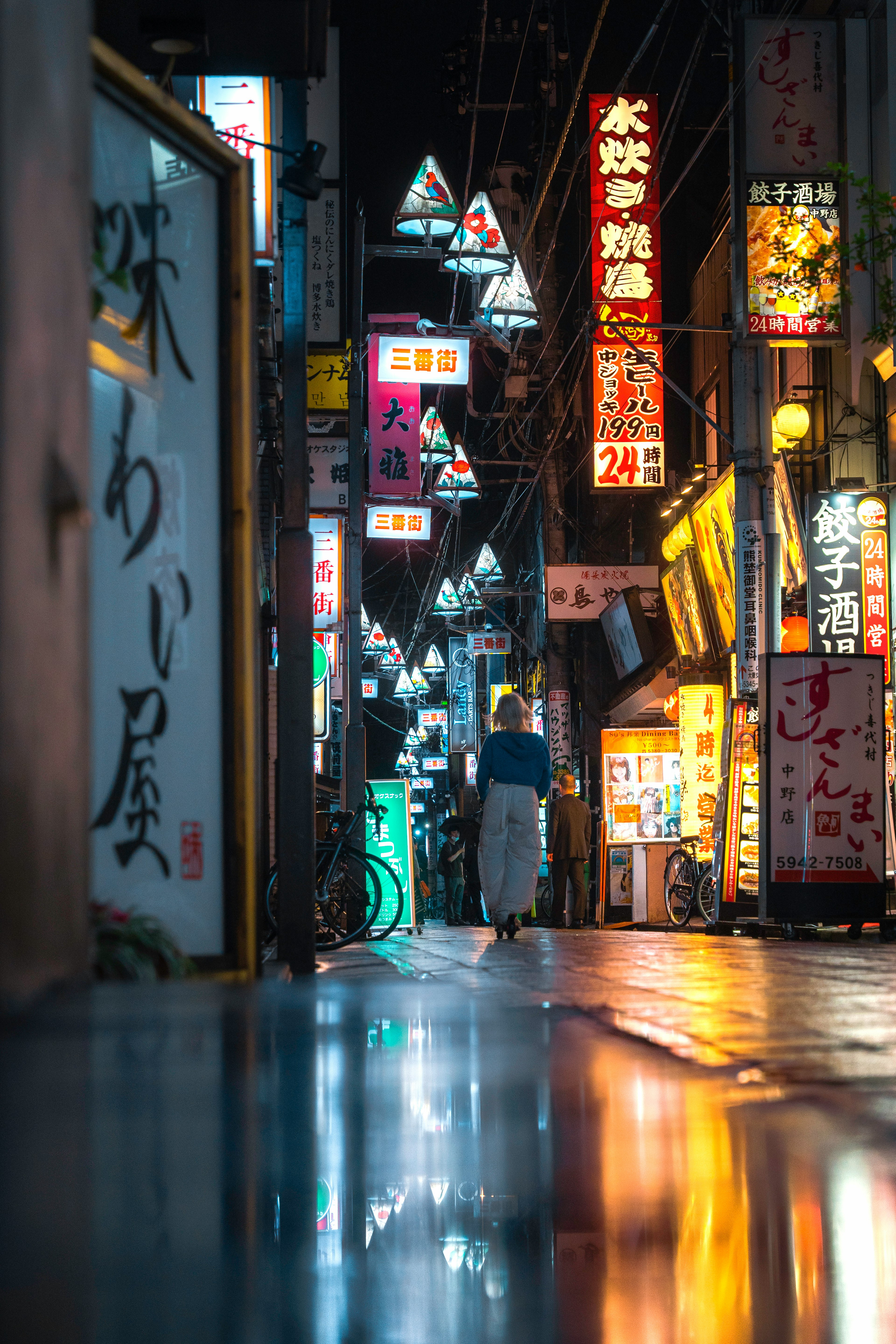 Vicolo stretto in Giappone di notte con insegne al neon colorate e riflessi