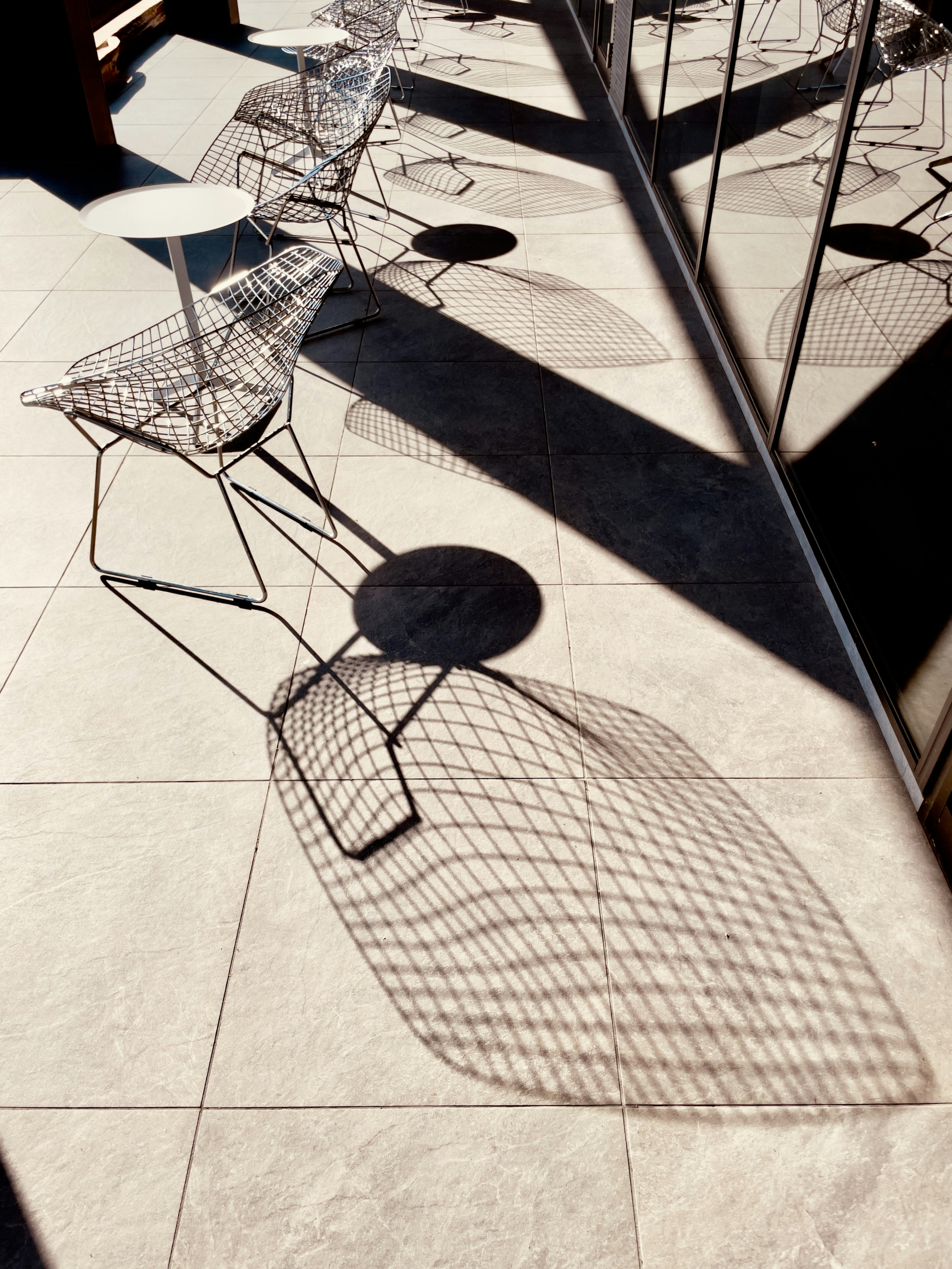 Elegant outdoor space with wire chairs and table casting shadows