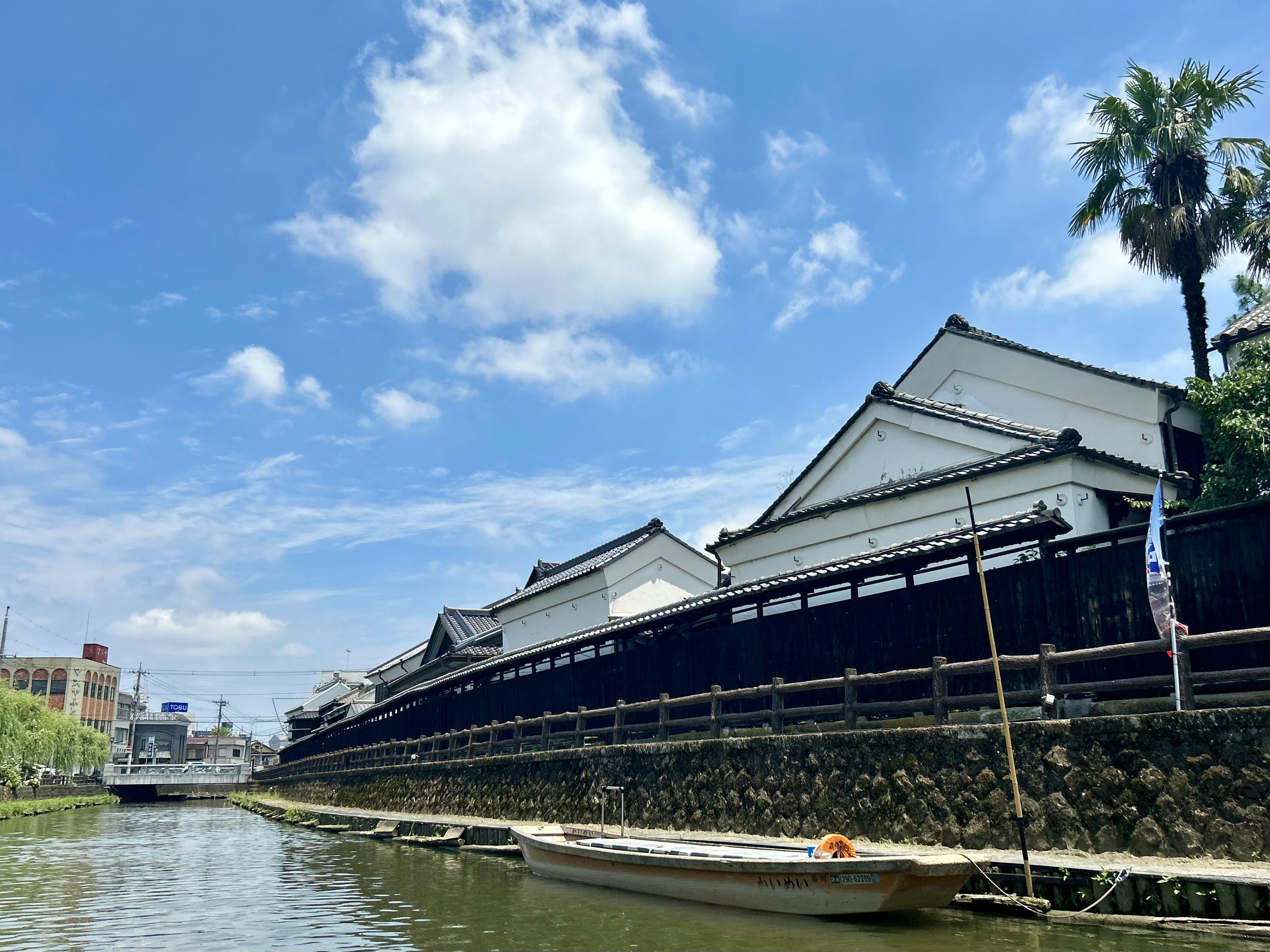 传统白色建筑沿水边排列，蓝天和云朵