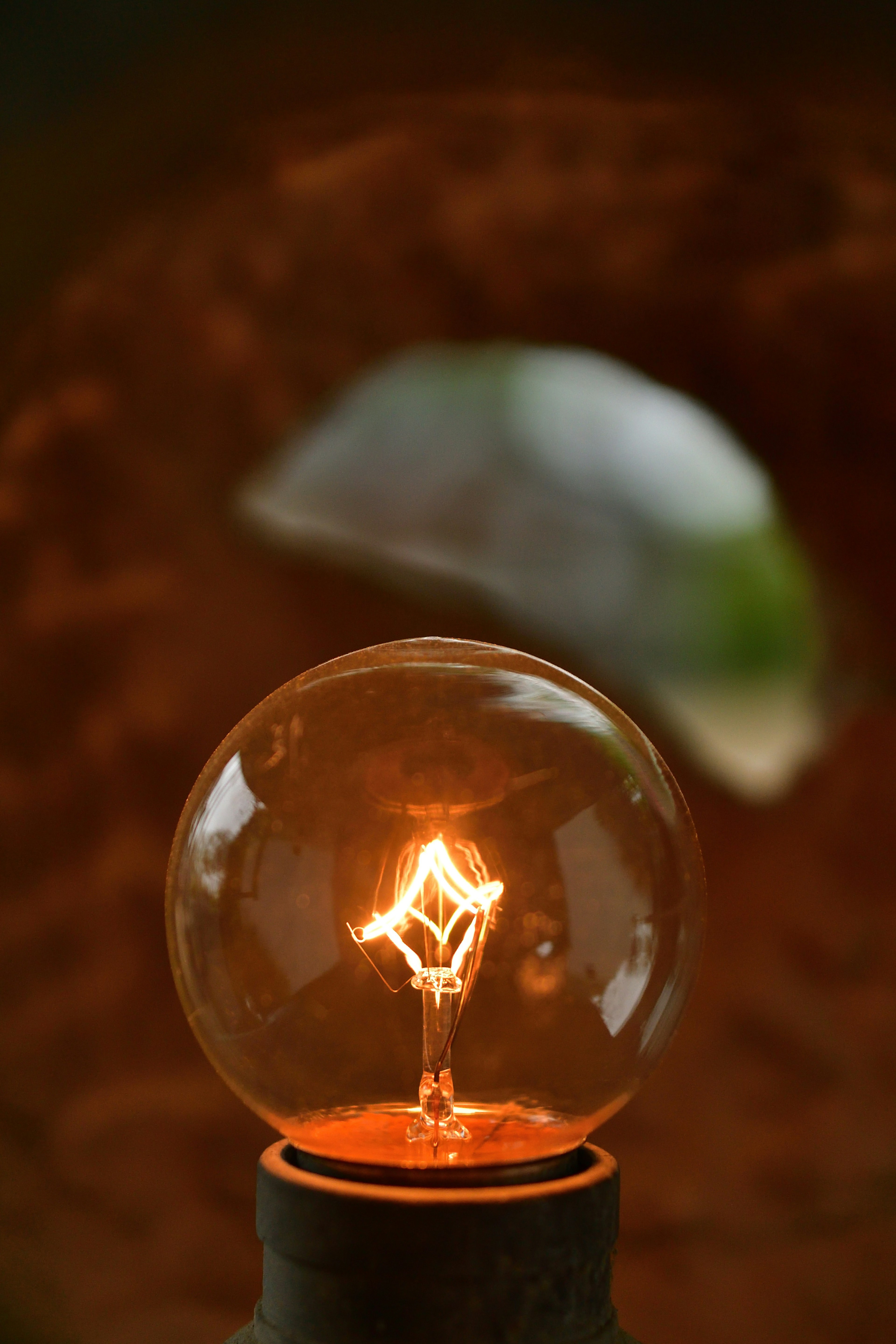 Close-up photo of a glowing light bulb with a blurred green object in the background