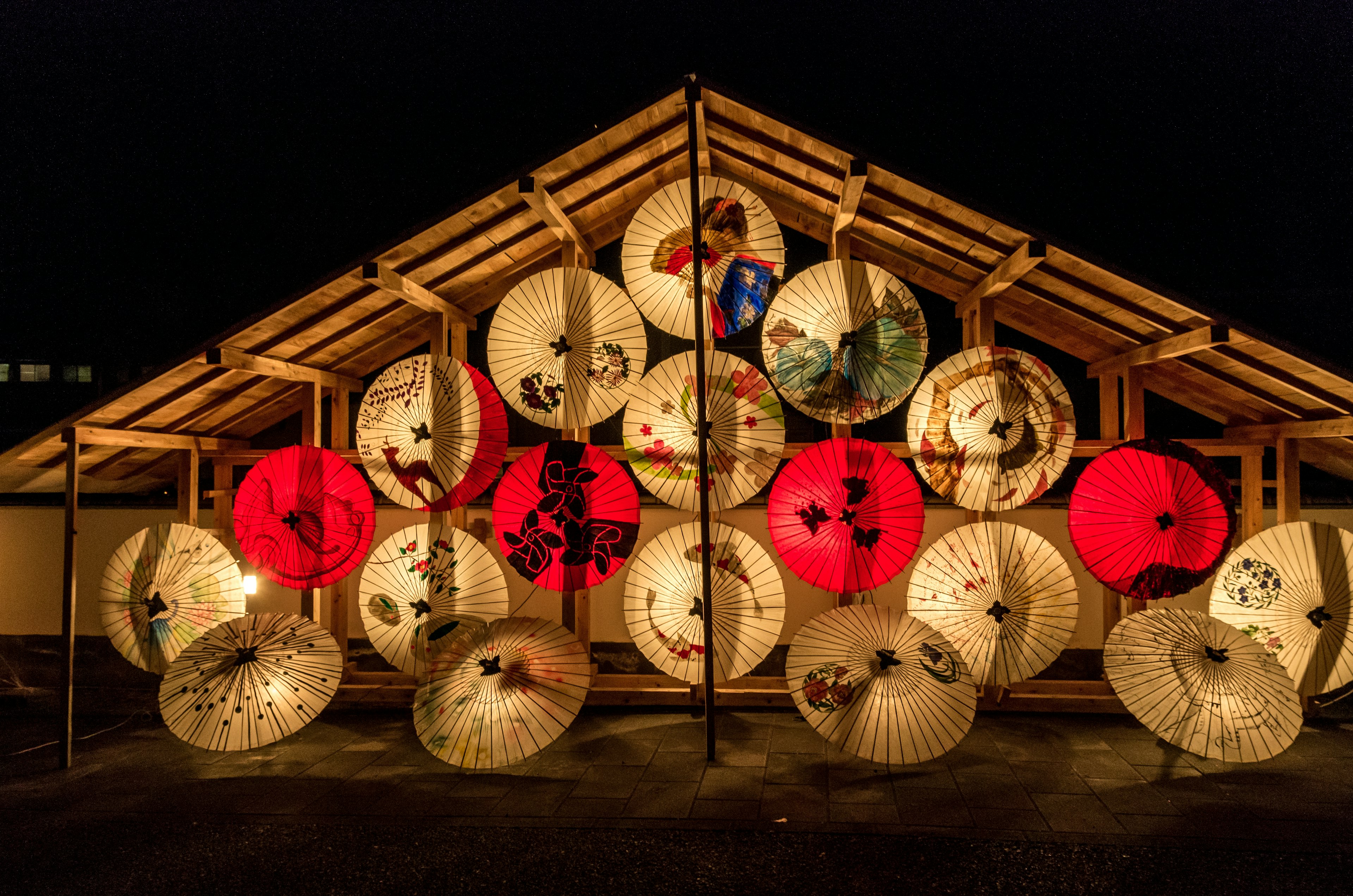 Colorful Japanese umbrellas displayed under a roof at night