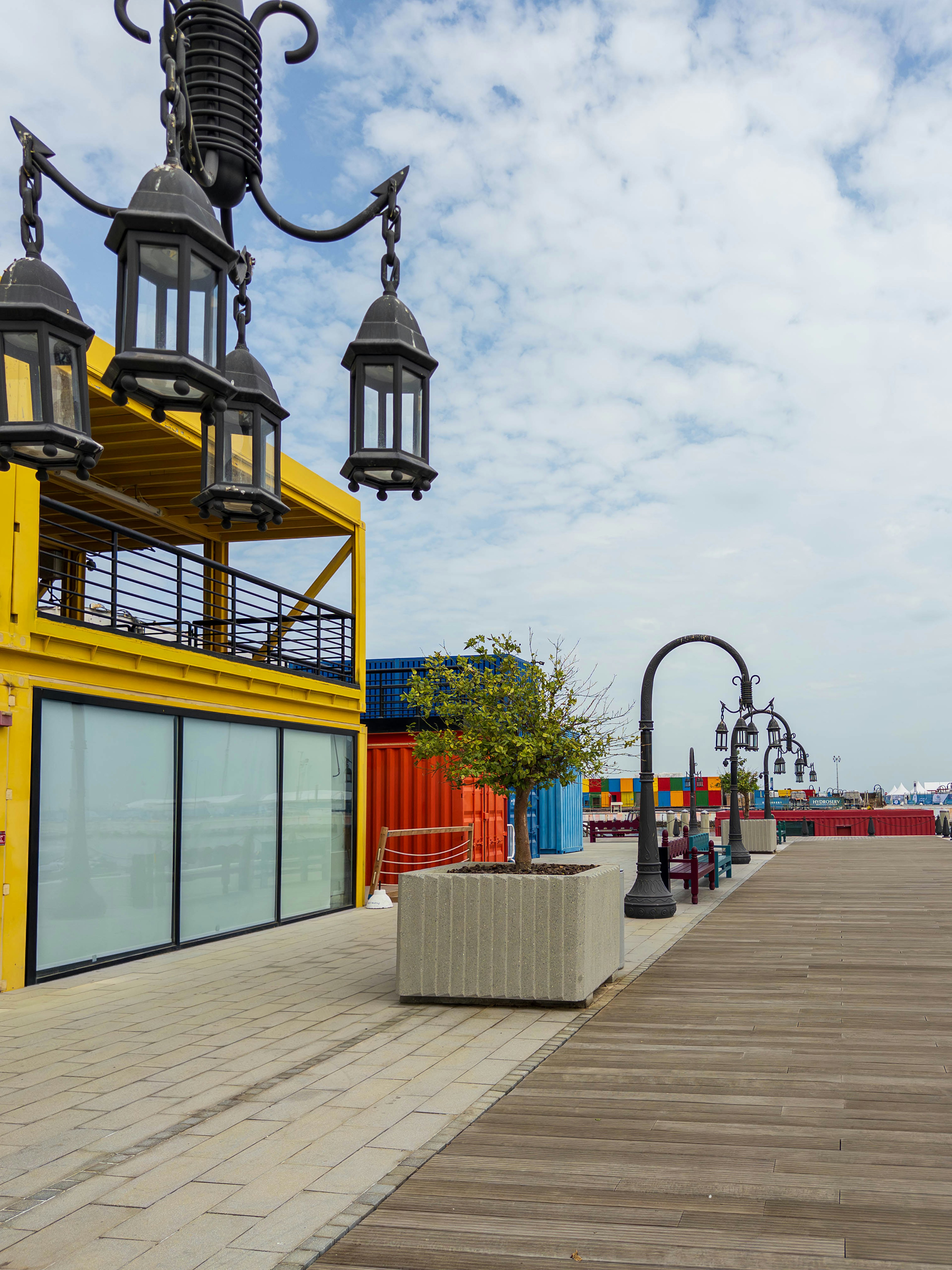 Vista de un paseo marítimo con un edificio amarillo brillante y farolas