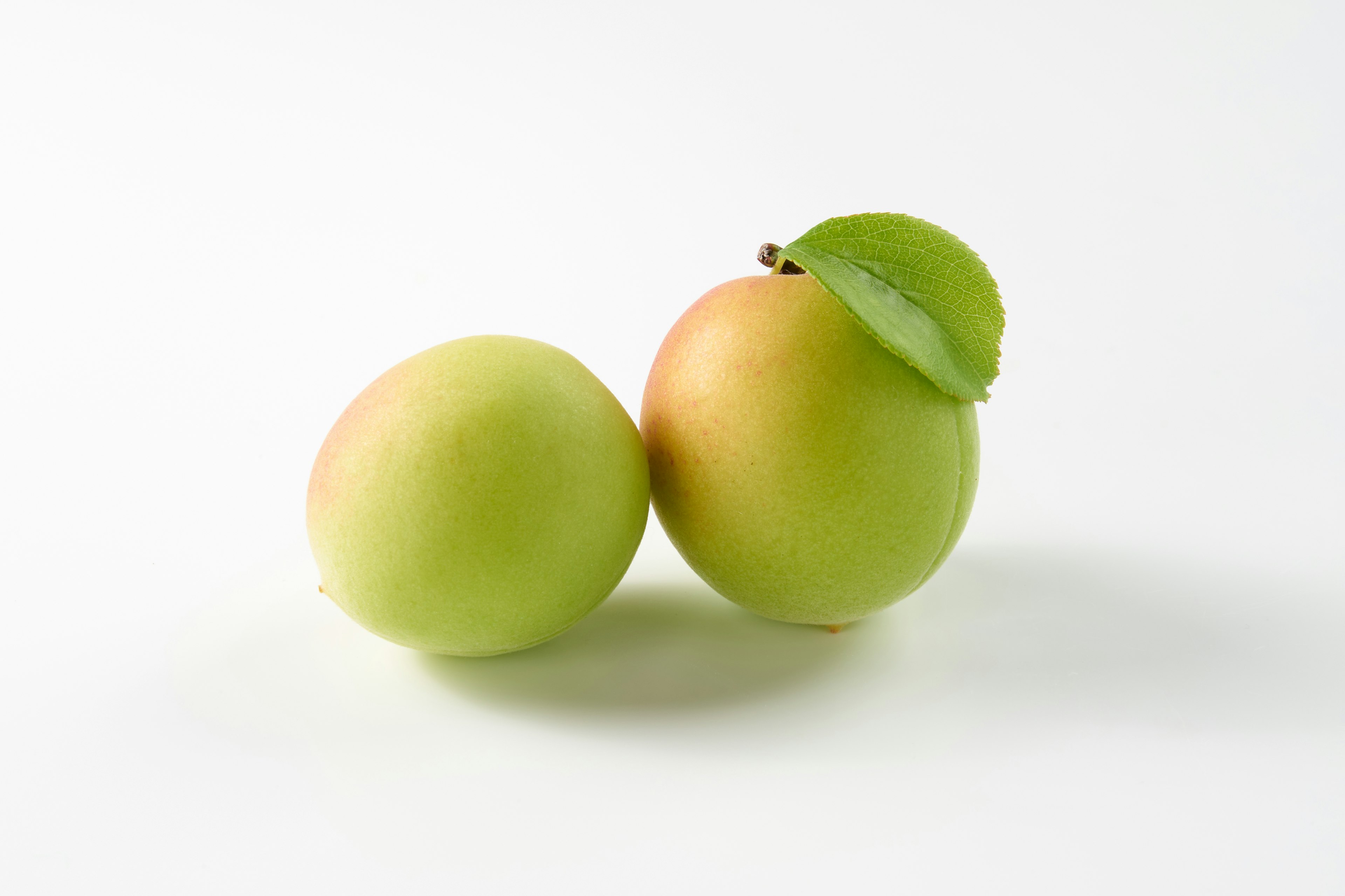 Dos manzanas verdes con un toque de amarillo sobre un fondo blanco