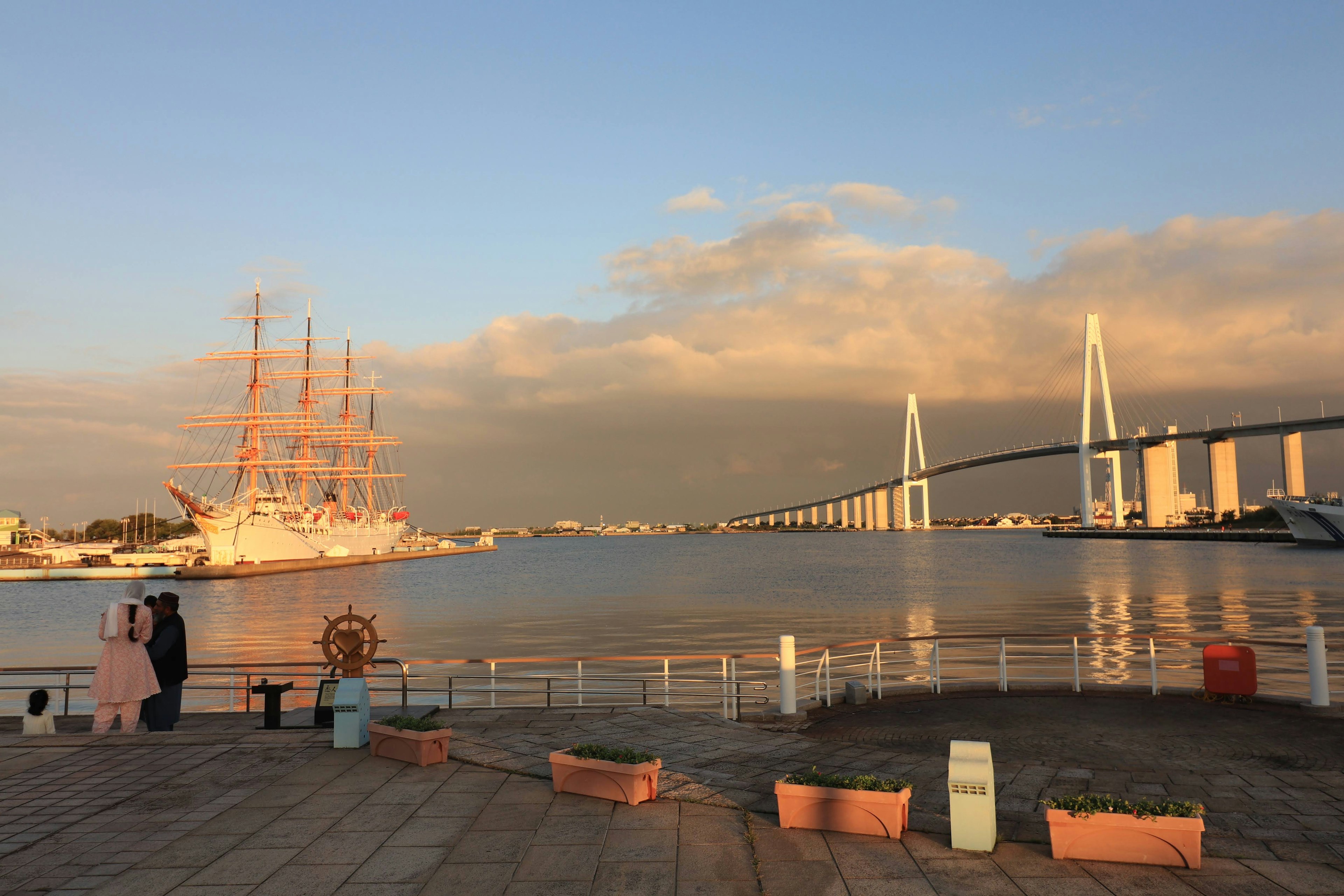 Scenic view of a sailing ship at sunset near a bridge