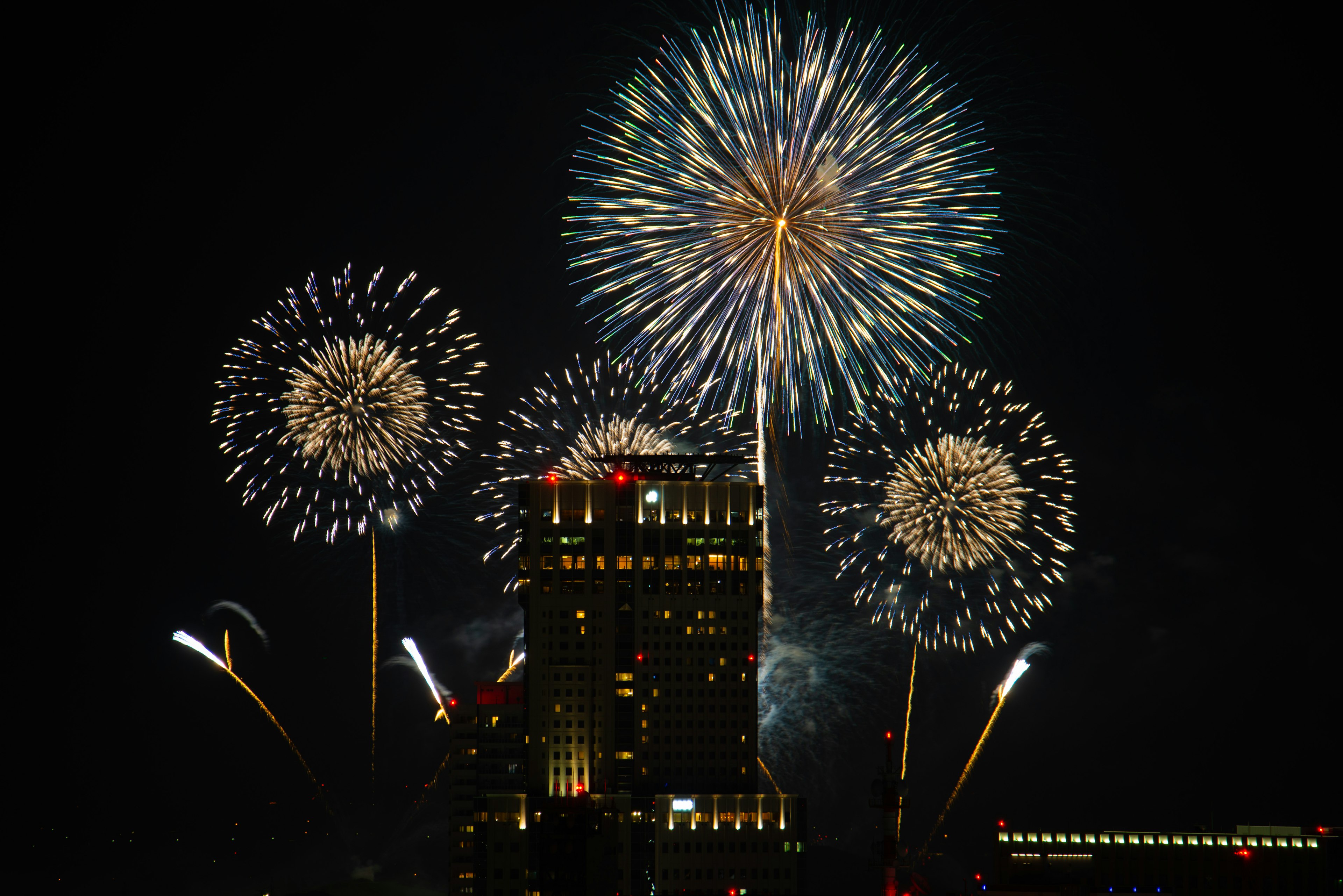 夜空に花火が打ち上がるシーン 高層ビルの前で色とりどりの火花が輝く