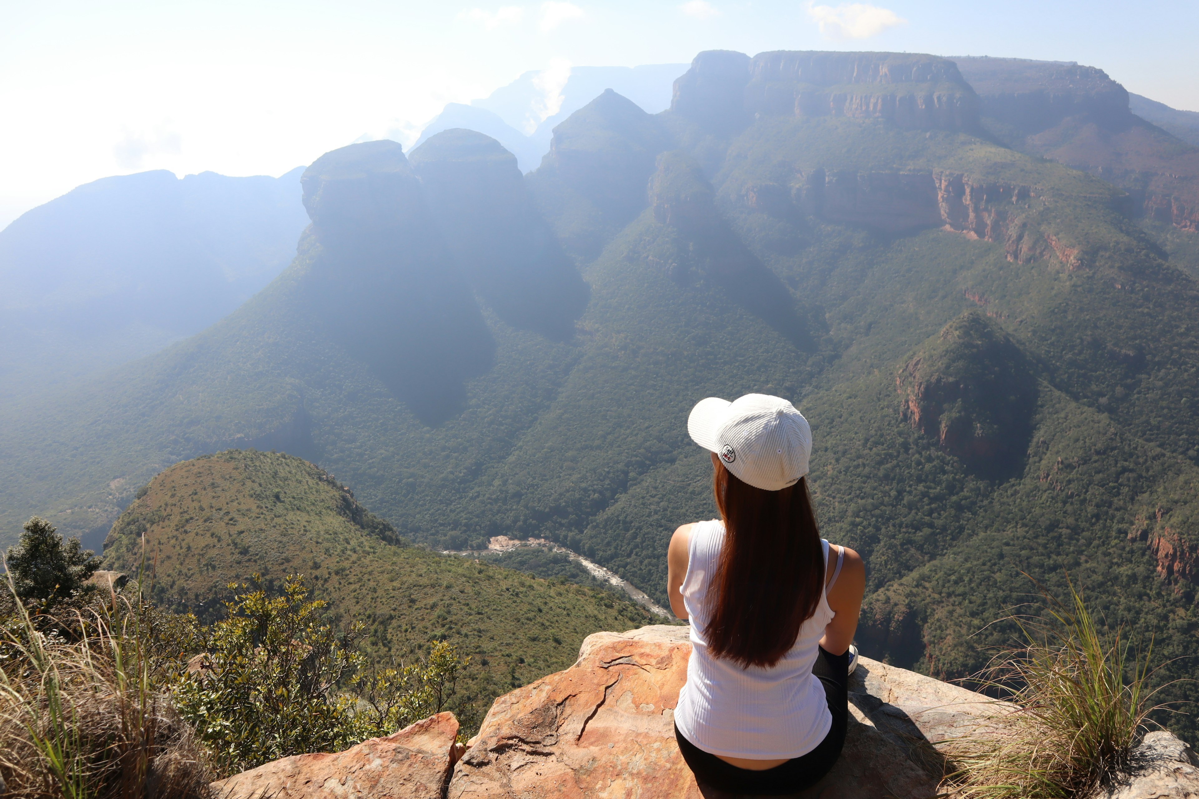 Une femme assise sur une roche avec une vue magnifique sur les montagnes