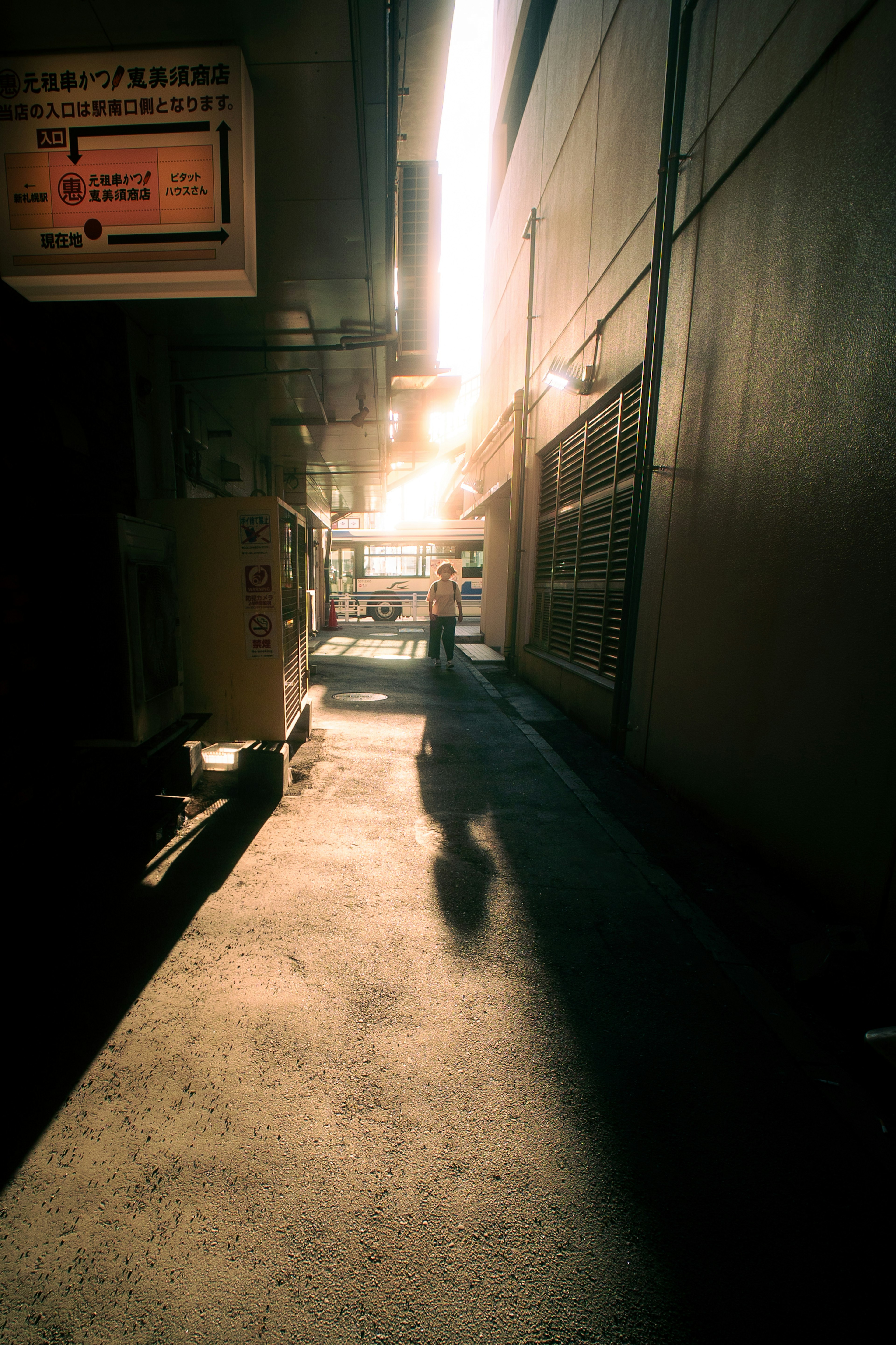 Schatten einer Person in einer engen Gasse, beleuchtet von hellem Licht