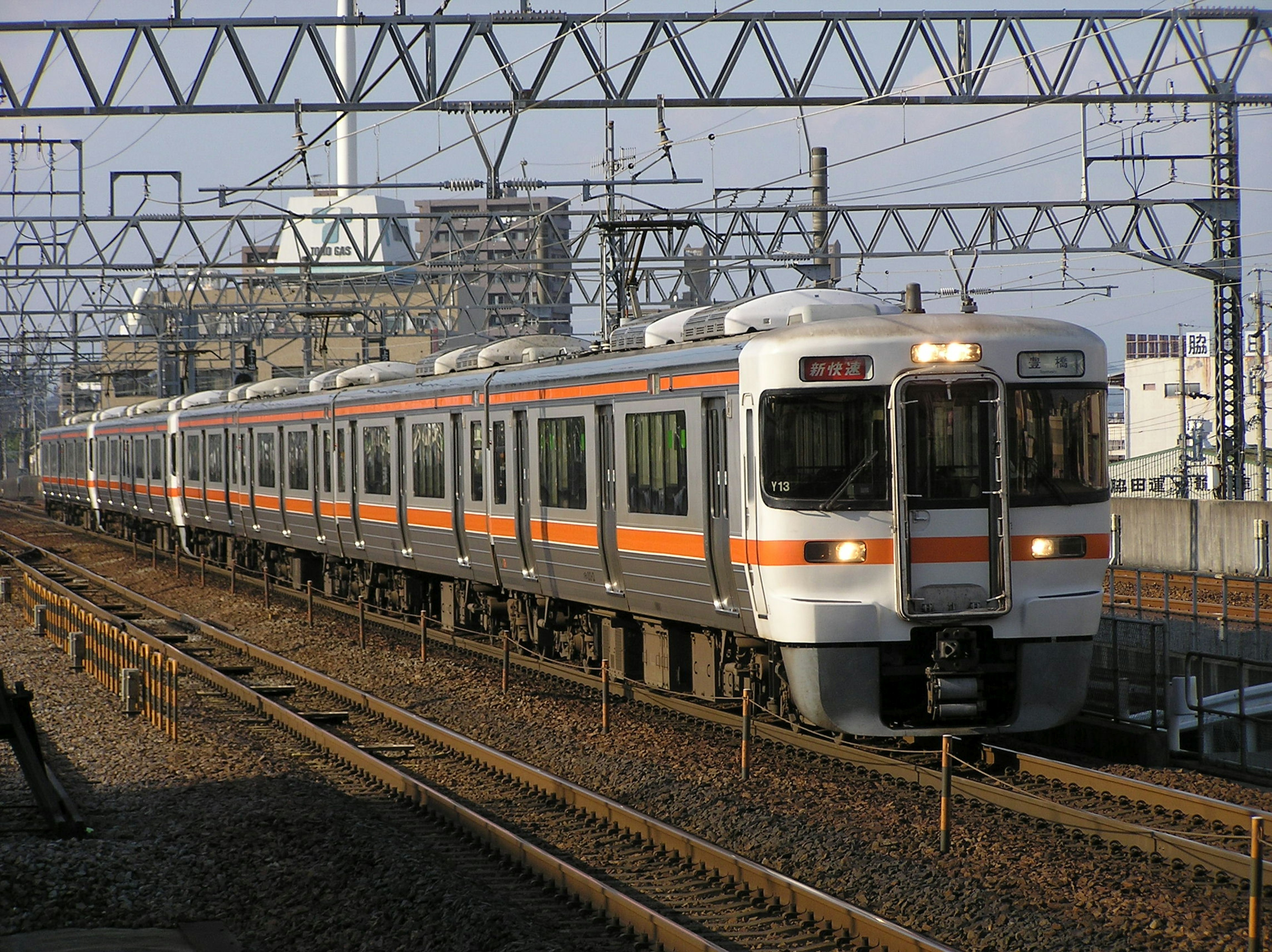 Ein japanischer Zug mit orangefarbenen Streifen, der über die Gleise fährt