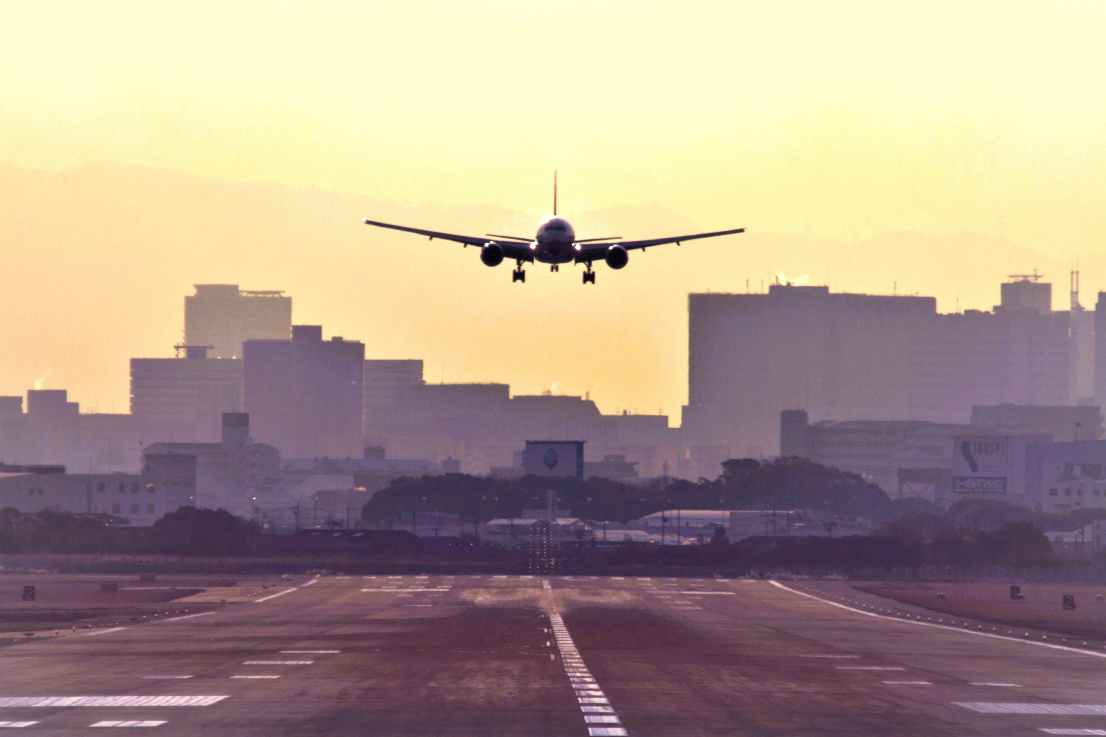 夕暮れ時に着陸する飛行機と背景の都市