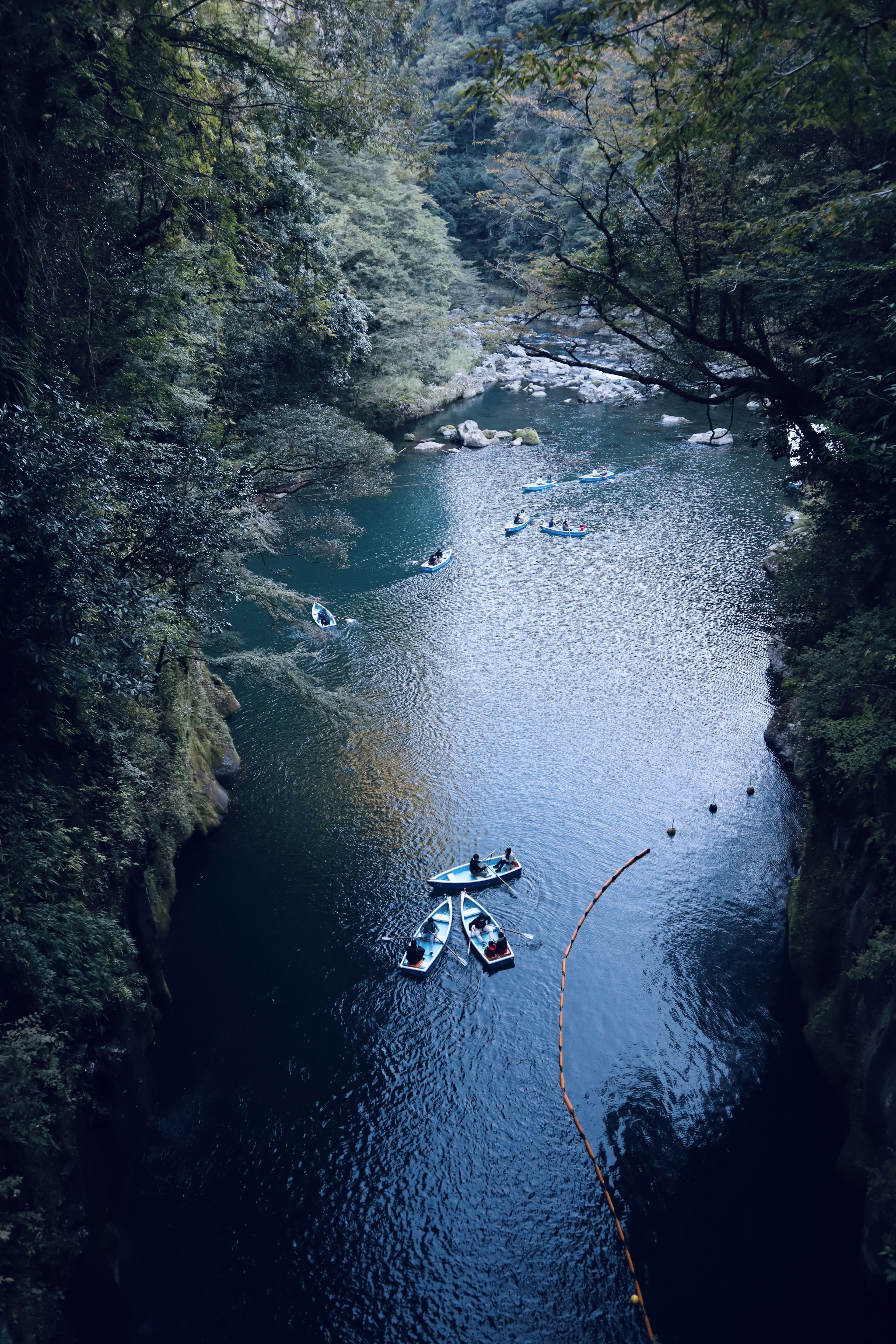 Kayaks floating on a blue river surrounded by green trees