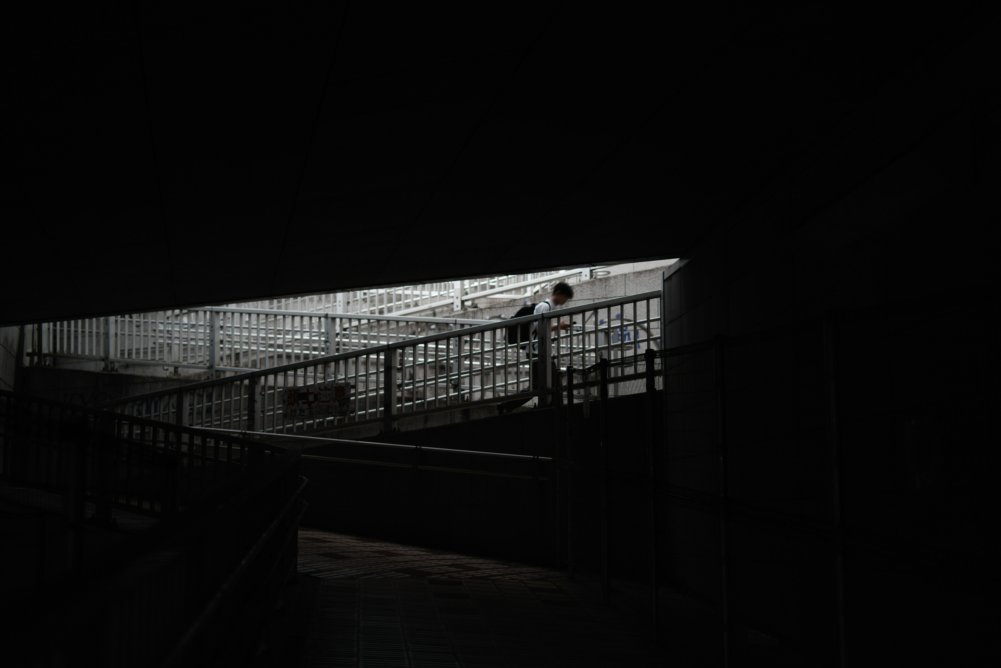 Silhouette d'une personne montant des escaliers lumineux dans un espace sombre