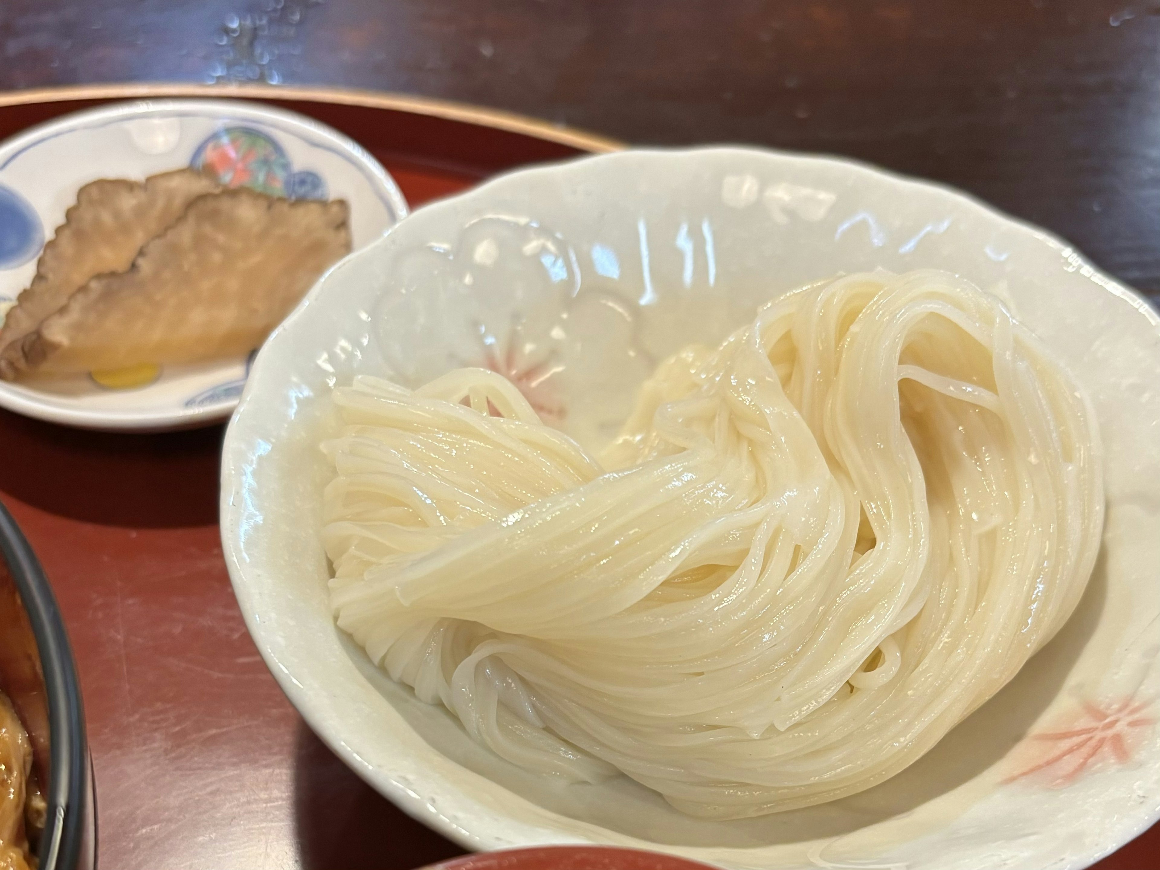 Un tazón de fideos blancos con un plato lateral