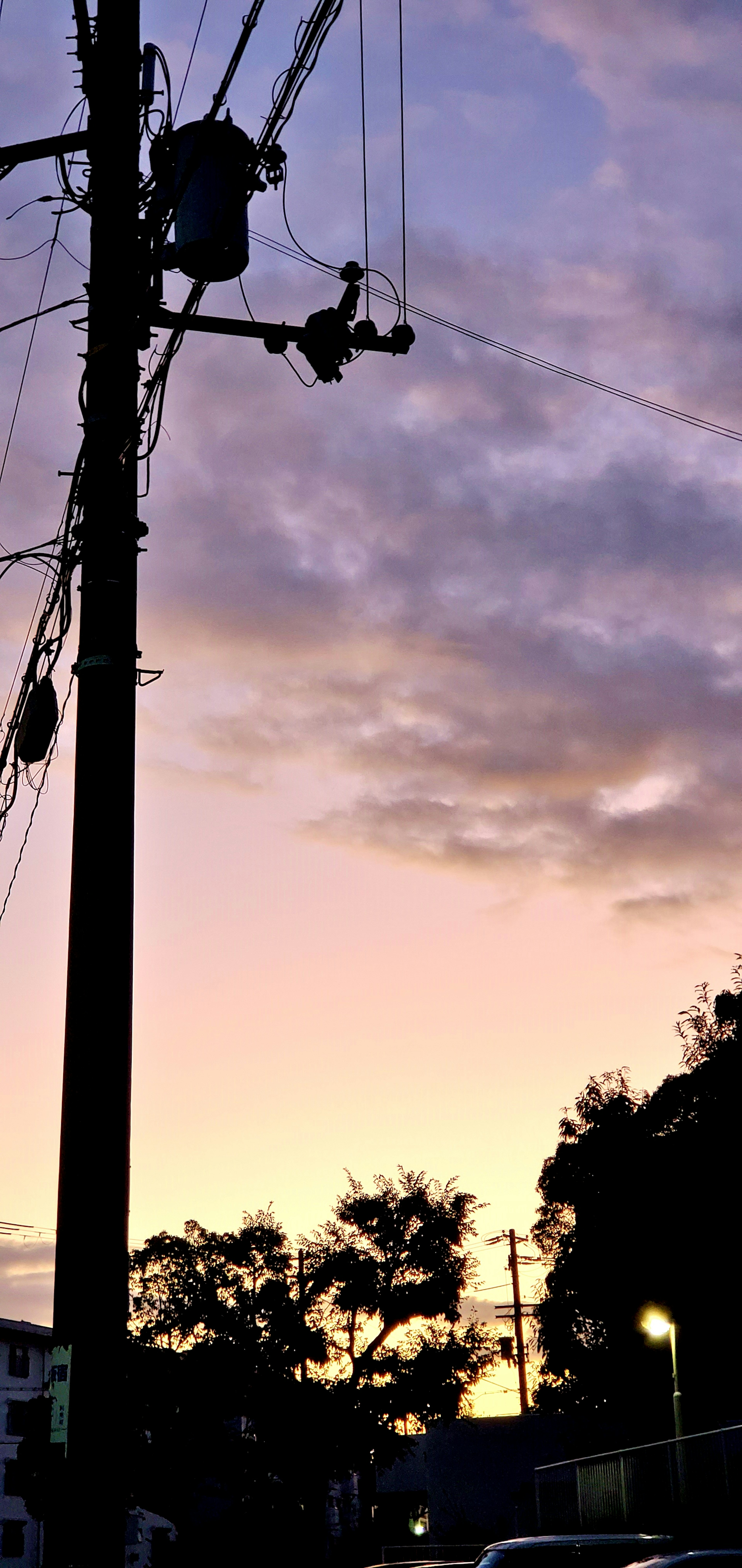 Silhouette of a utility pole against a sunset sky