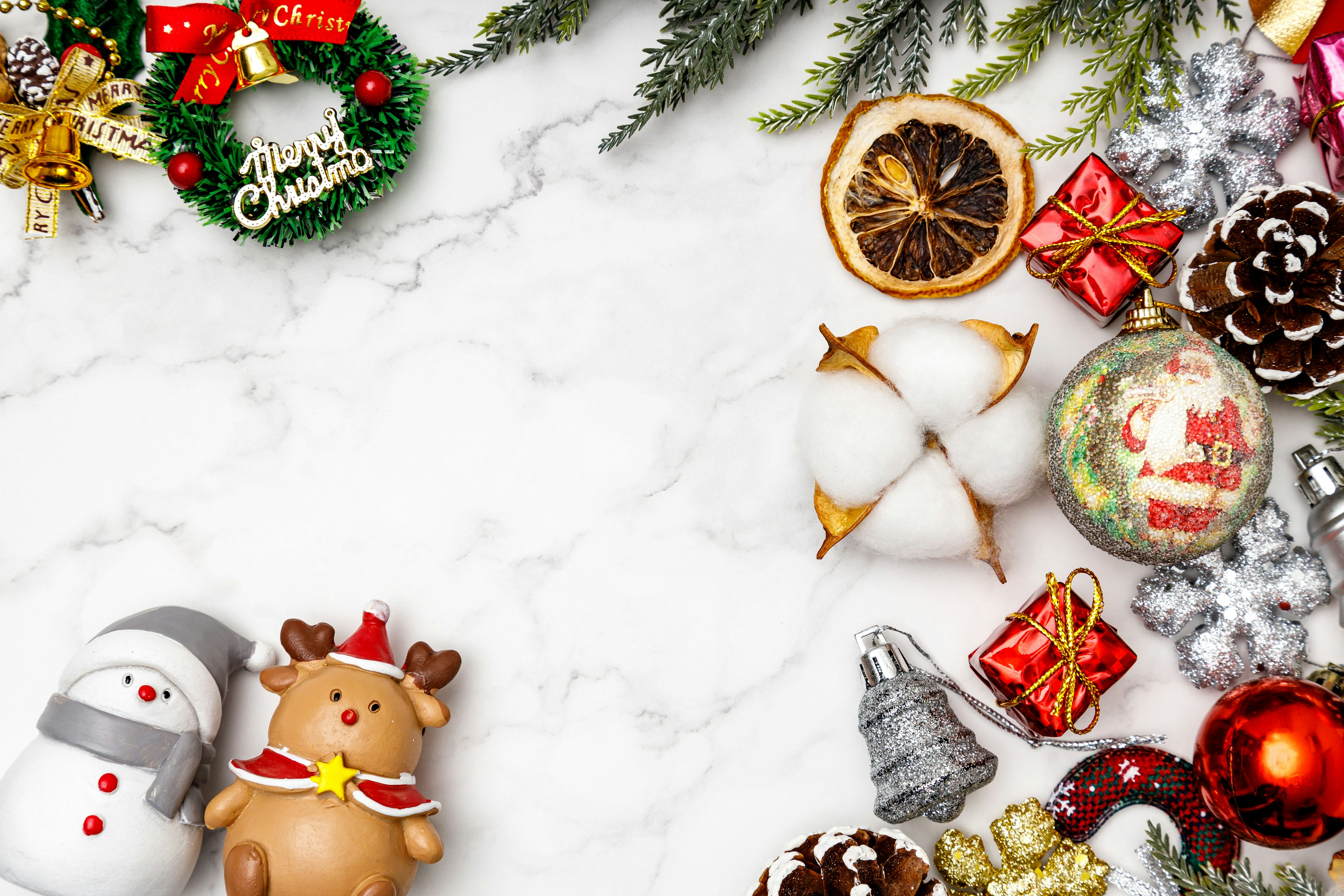 Christmas decorations including a snowman, reindeer, and ornaments on a marble surface