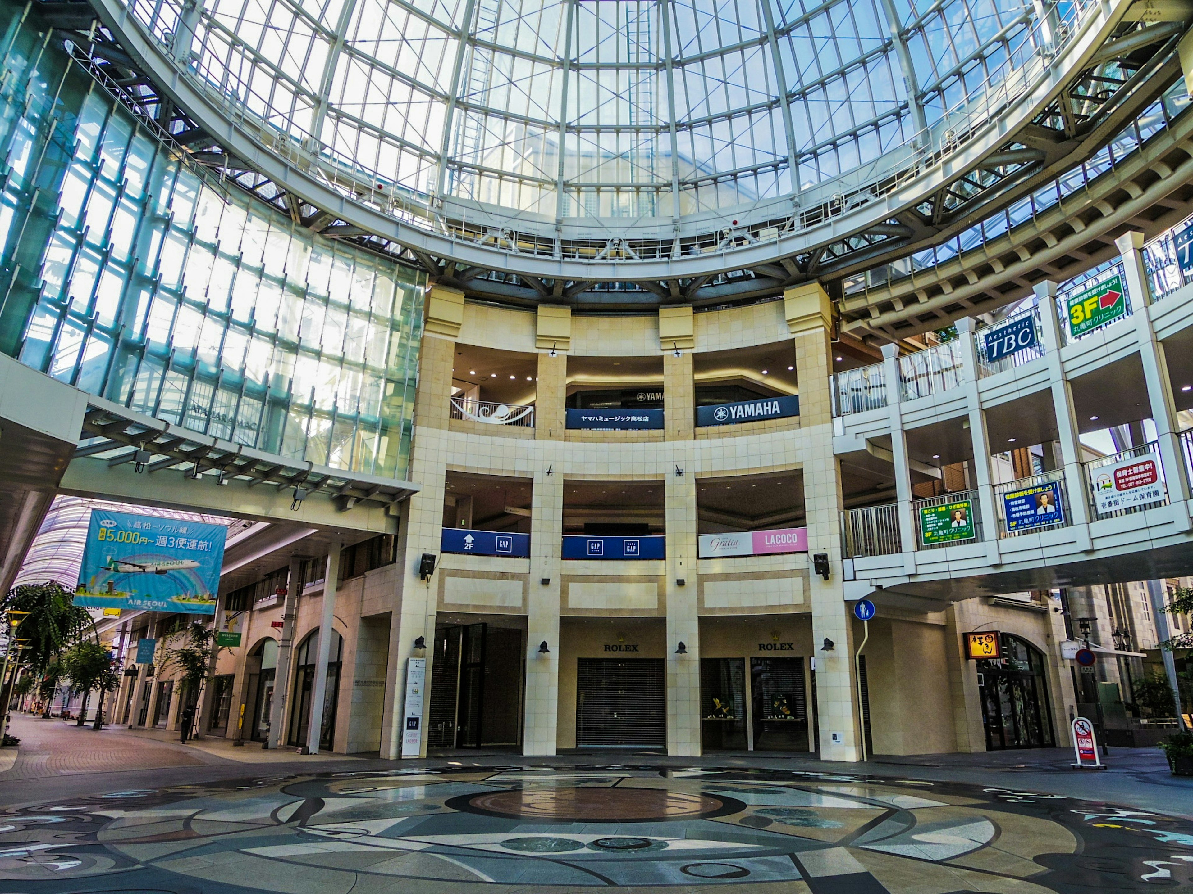 Interior de un espacio comercial con un gran techo de vidrio