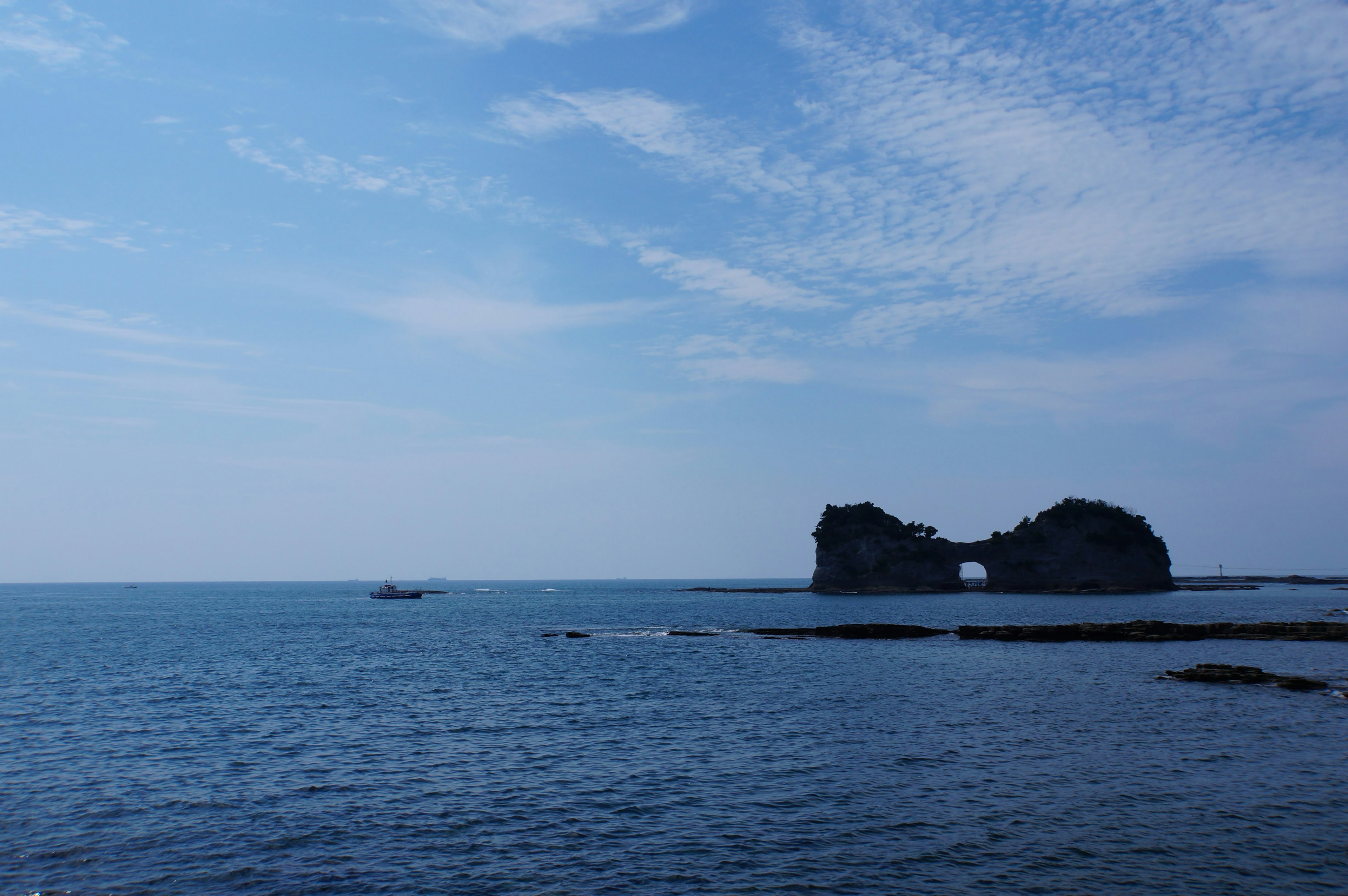 青空と静かな海に浮かぶ岩の島