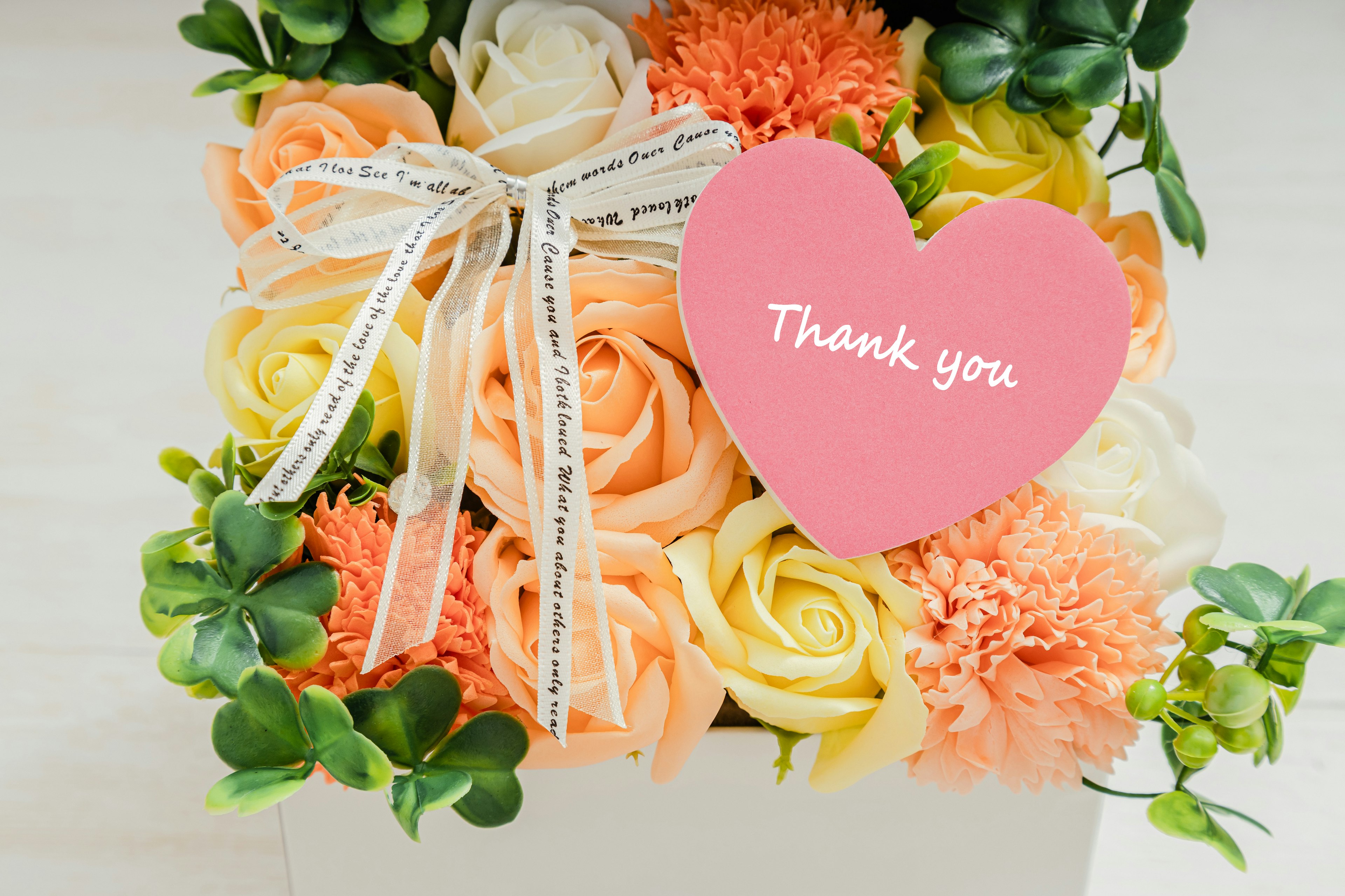 Flower arrangement with a pink heart-shaped card saying thank you