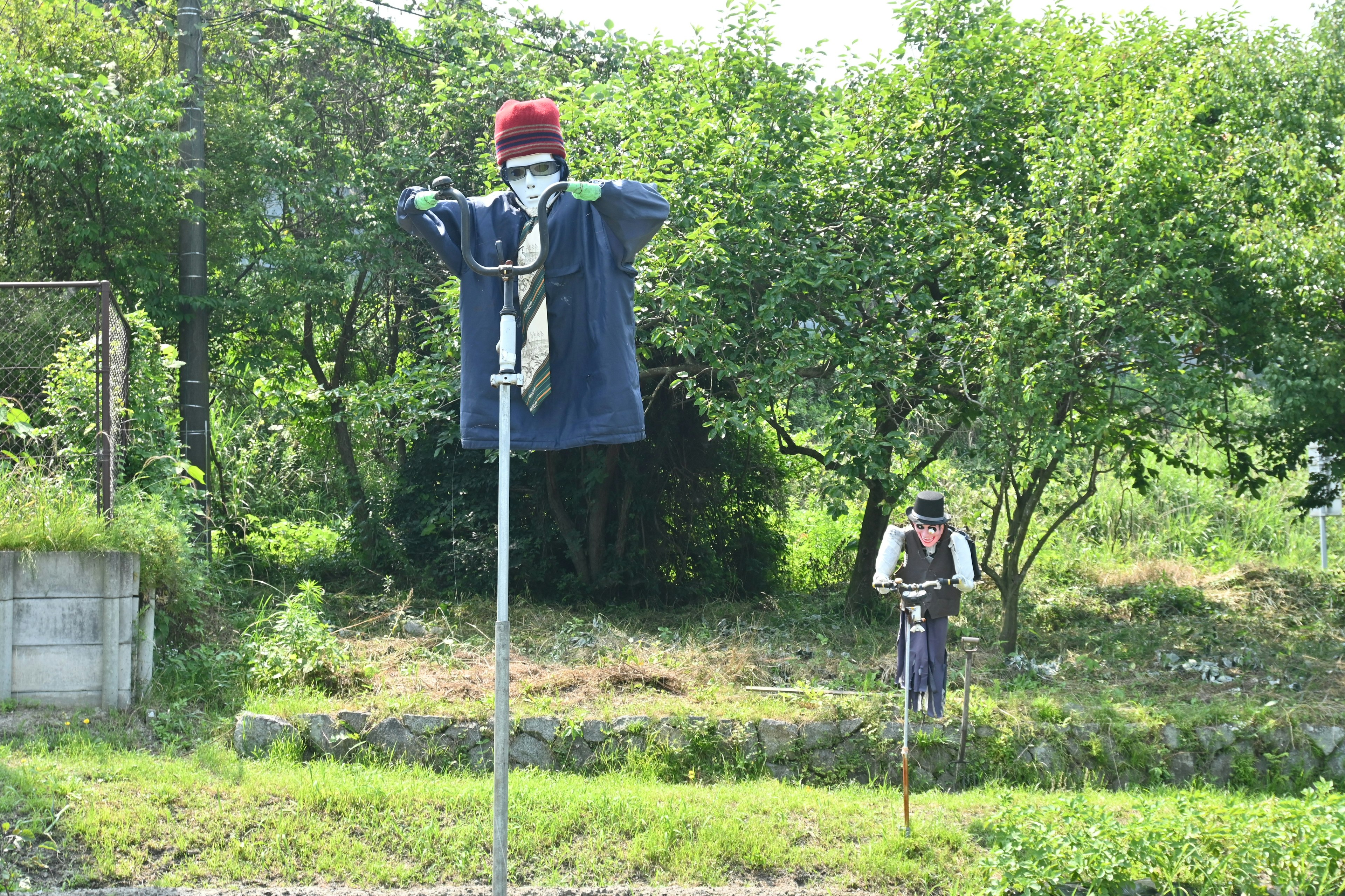 Vogelscheuche steht auf einem Feld mit einer Person, die in der Nähe arbeitet