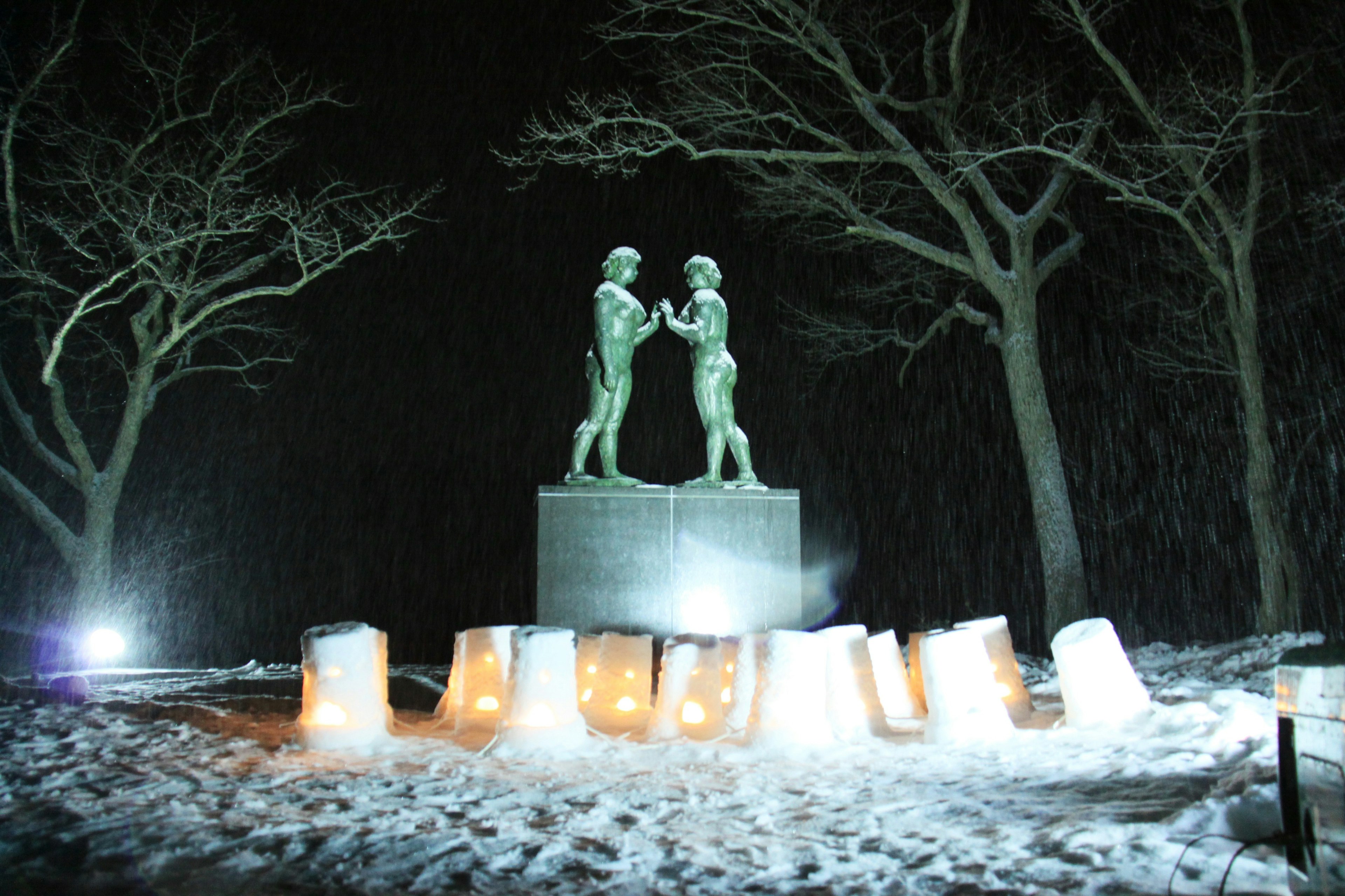 Statue de deux figures debout dans la neige avec des blocs de glace lumineux autour