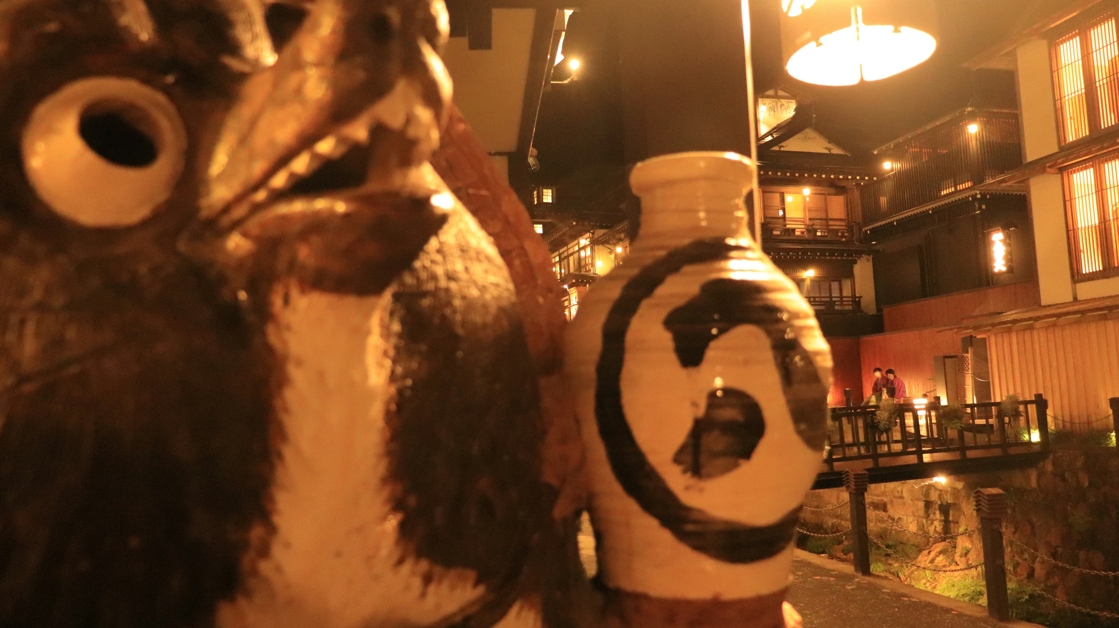 Ceramic tanuki statue and jar in a Japanese street at night