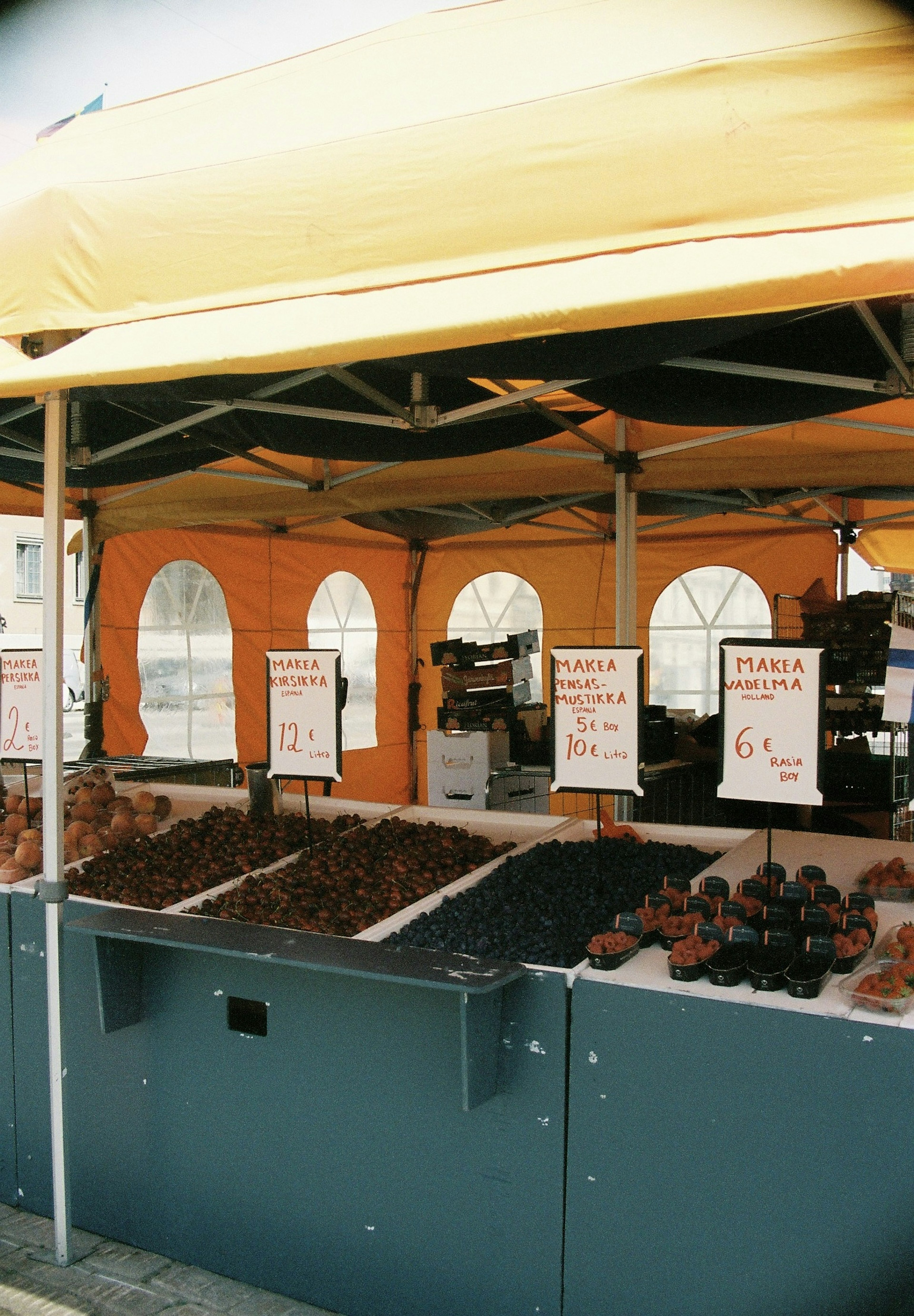 Chiosco di mercato sotto una tenda arancione che espone vari frutti secchi e noci