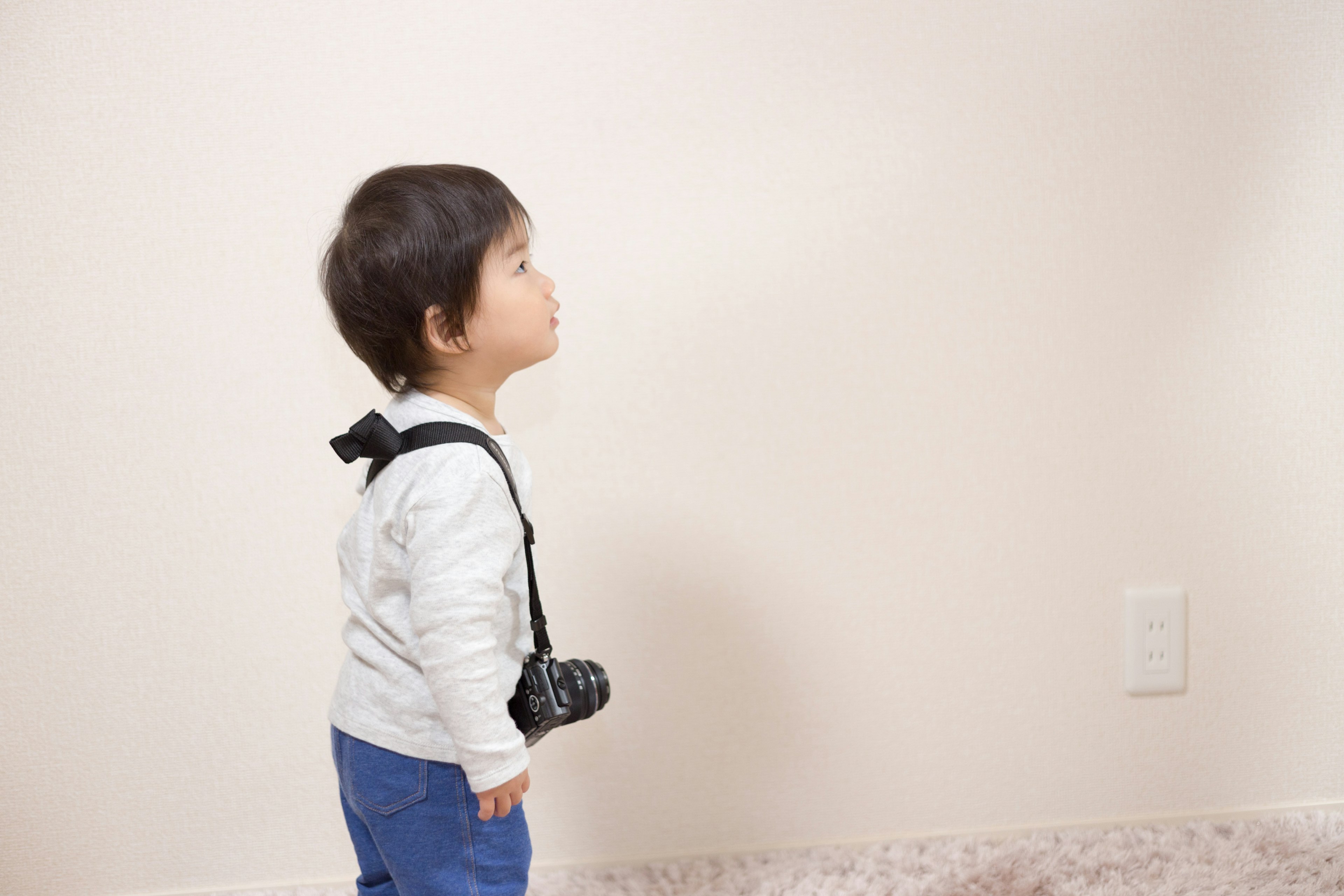 Un bambino con una macchina fotografica che guarda un muro