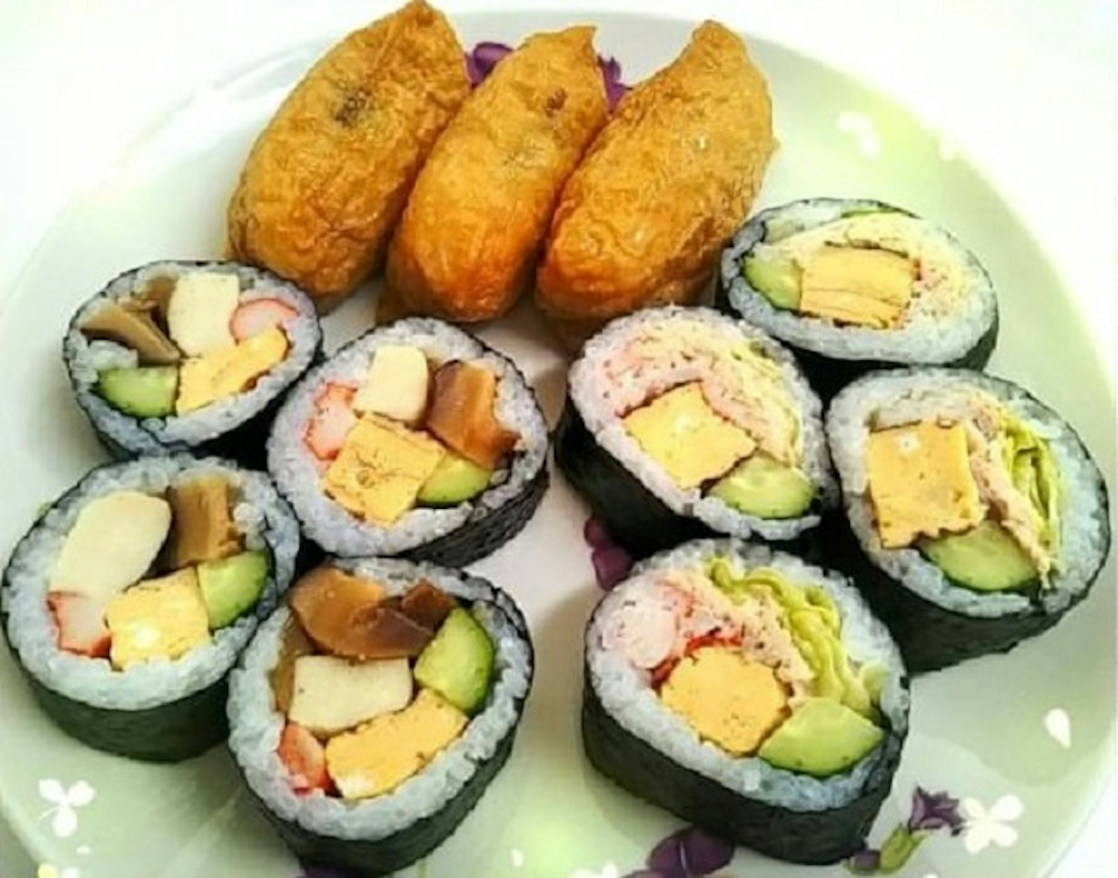 Platter of sushi featuring rolled sushi with various fillings wrapped in black seaweed and fried inari sushi