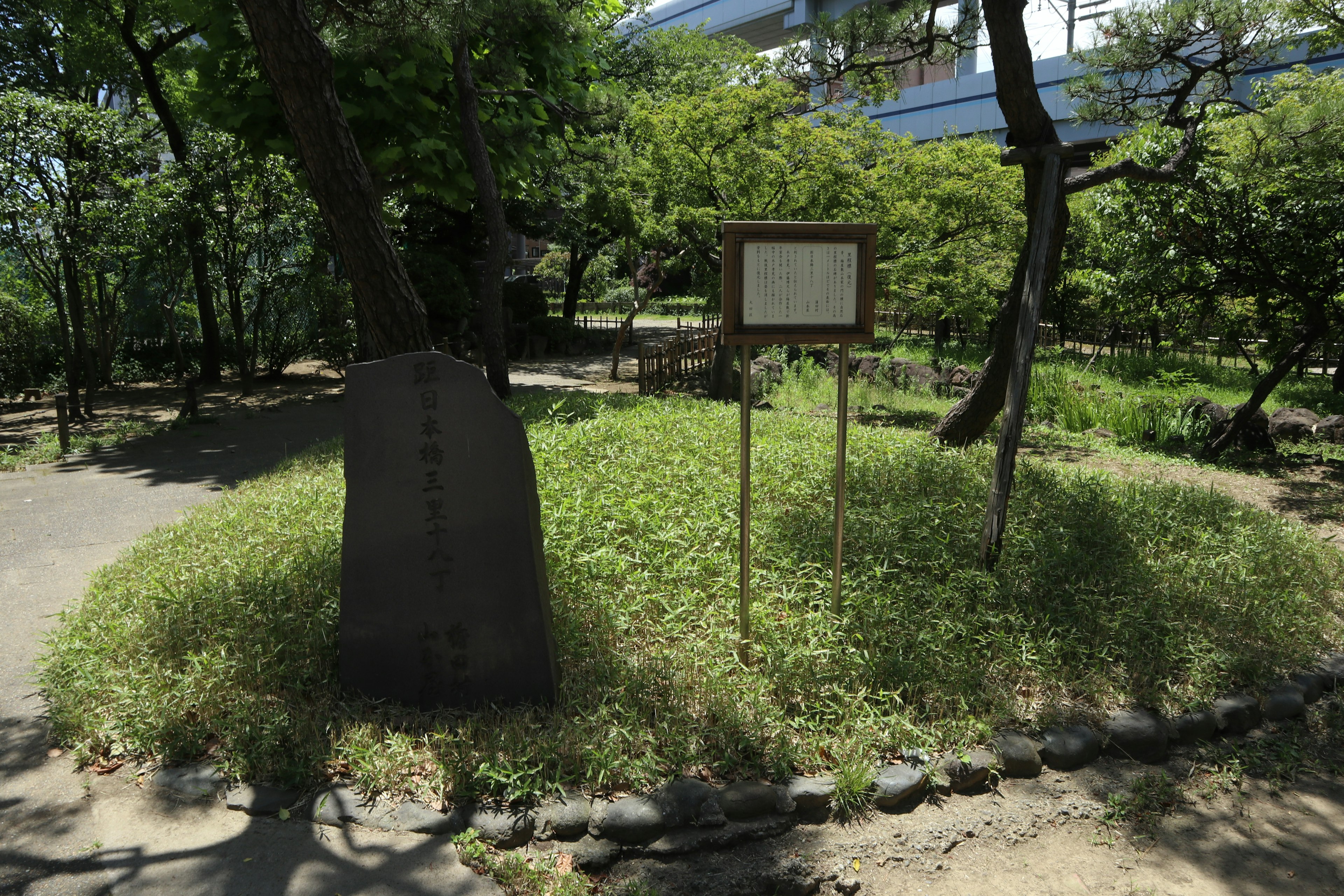 Pemandangan monumen batu dan papan informasi di taman hijau