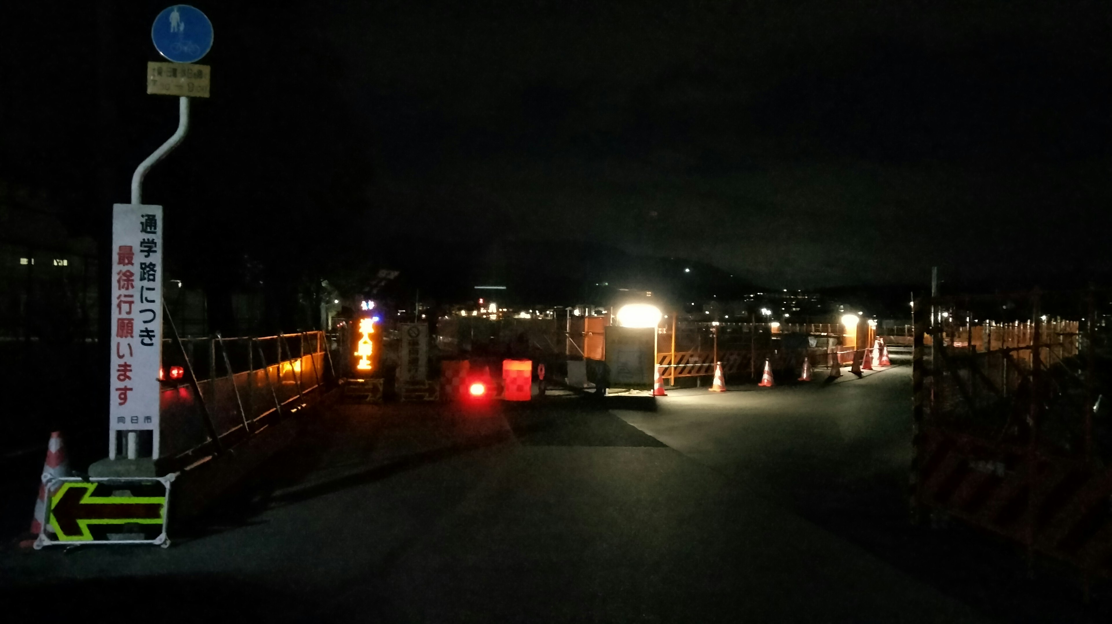 Nighttime construction site scene with working lights and visible traffic signs