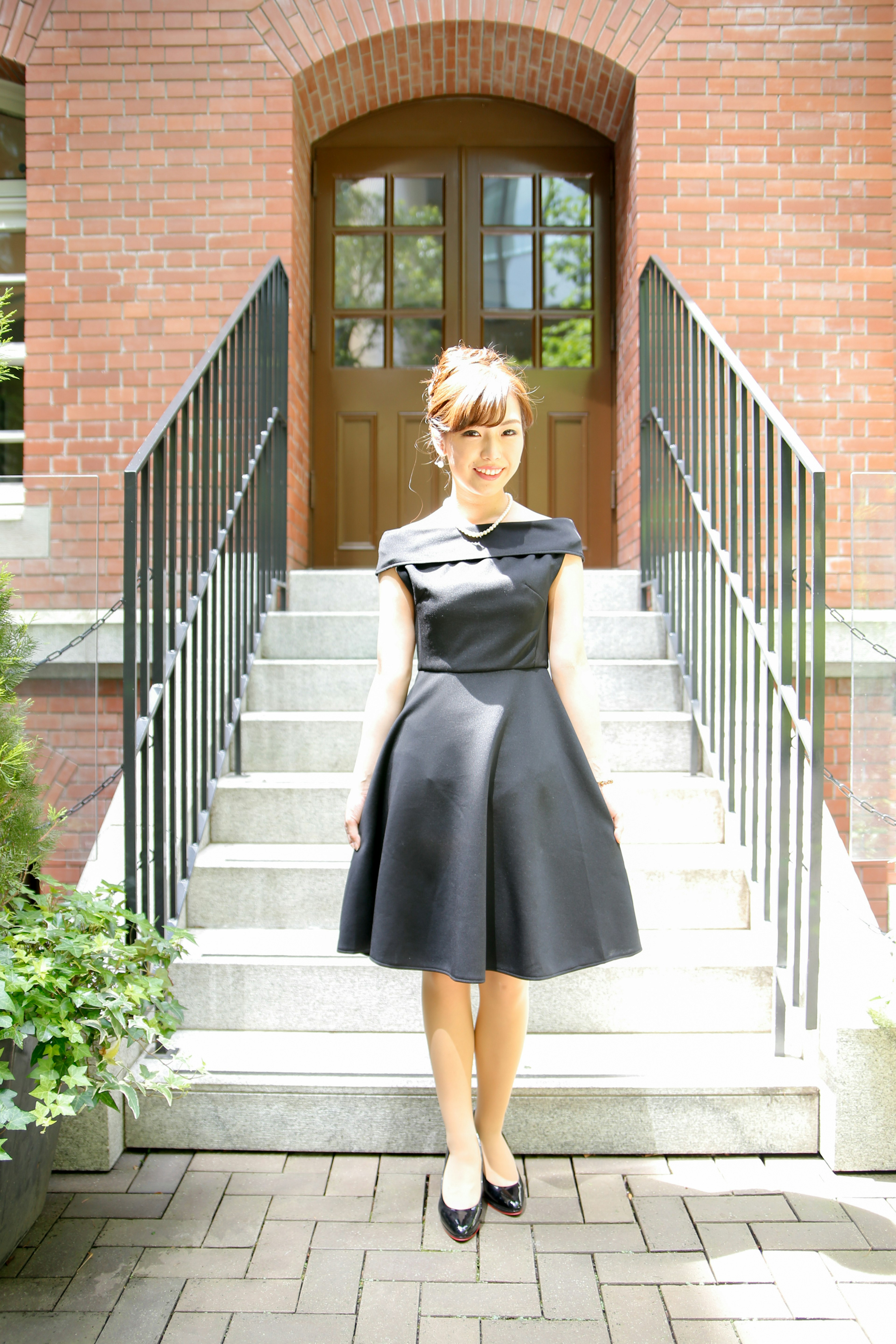 A woman wearing a black dress standing on stairs