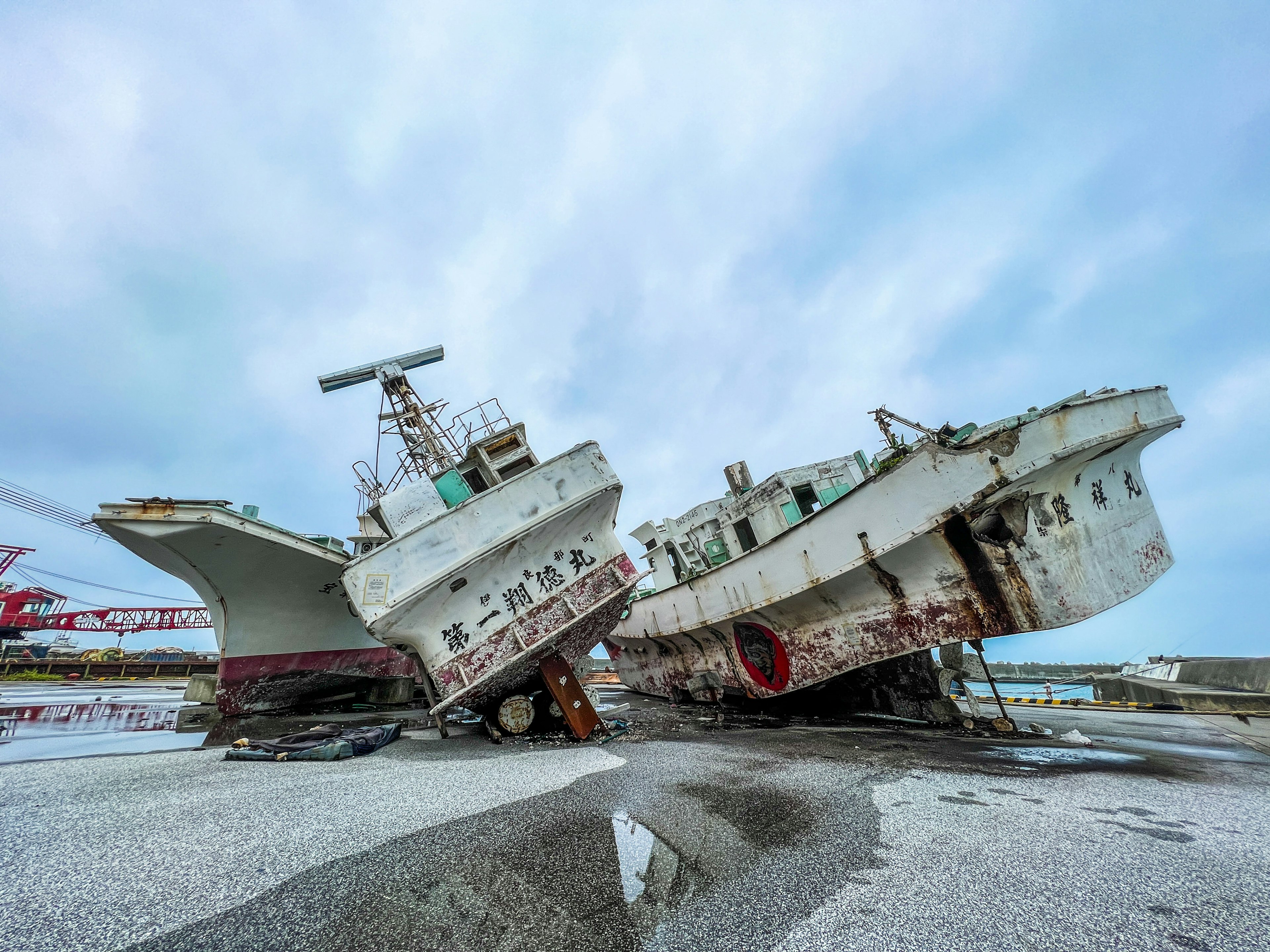 Two tilted ships side by side on a rocky shore