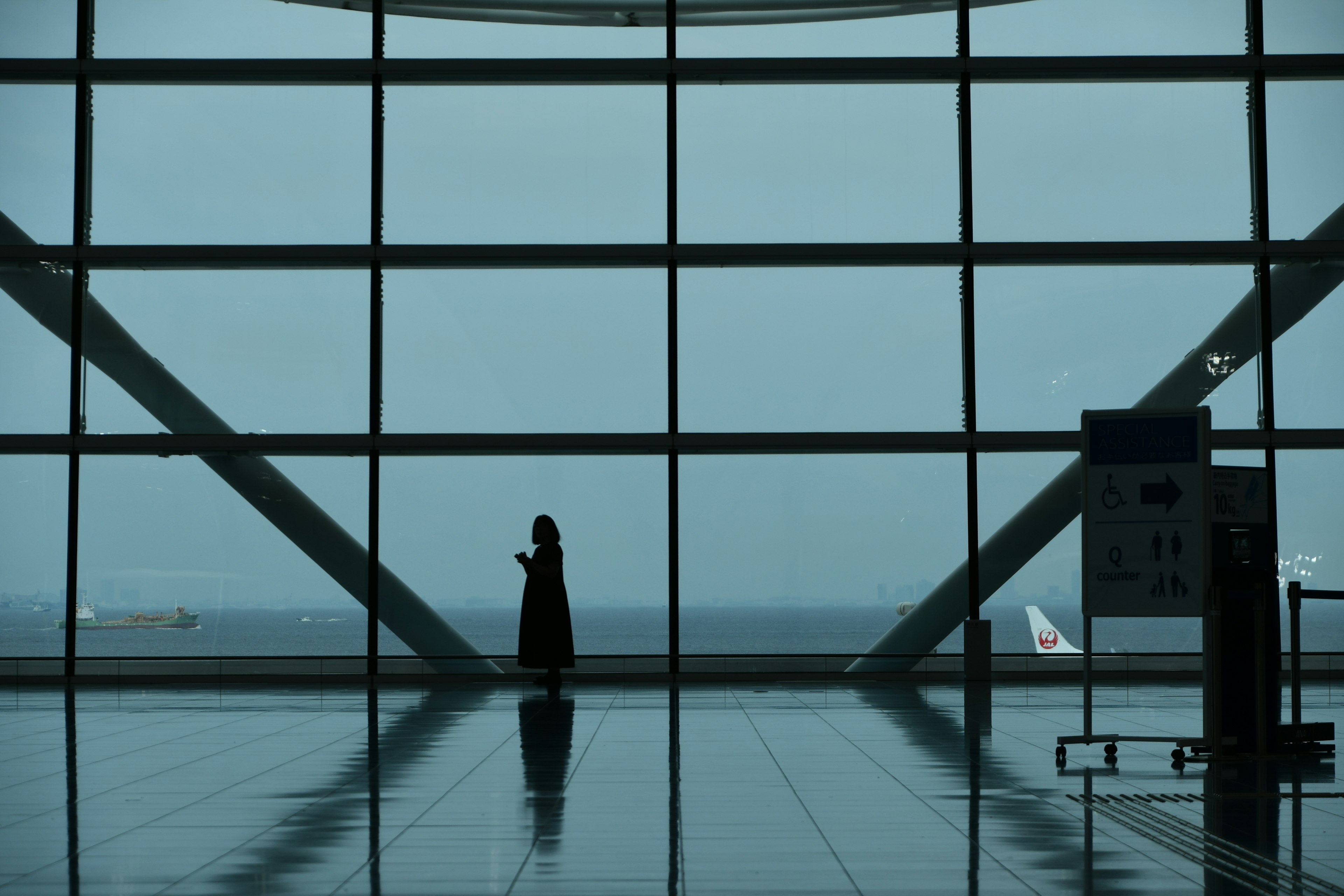 Silueta de una mujer de pie frente a grandes ventanas del aeropuerto