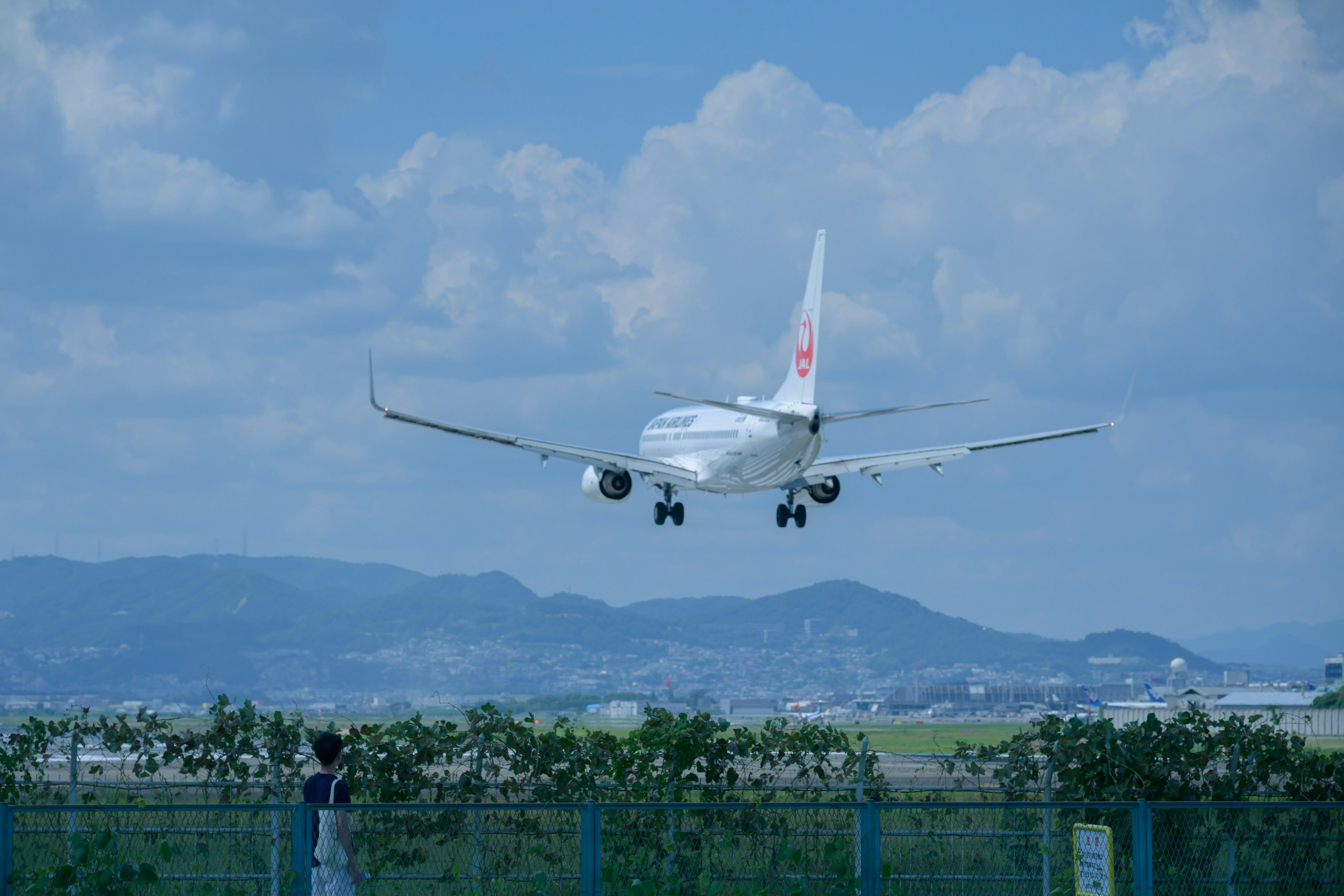 Avion atterrissant contre un ciel bleu avec des montagnes en arrière-plan