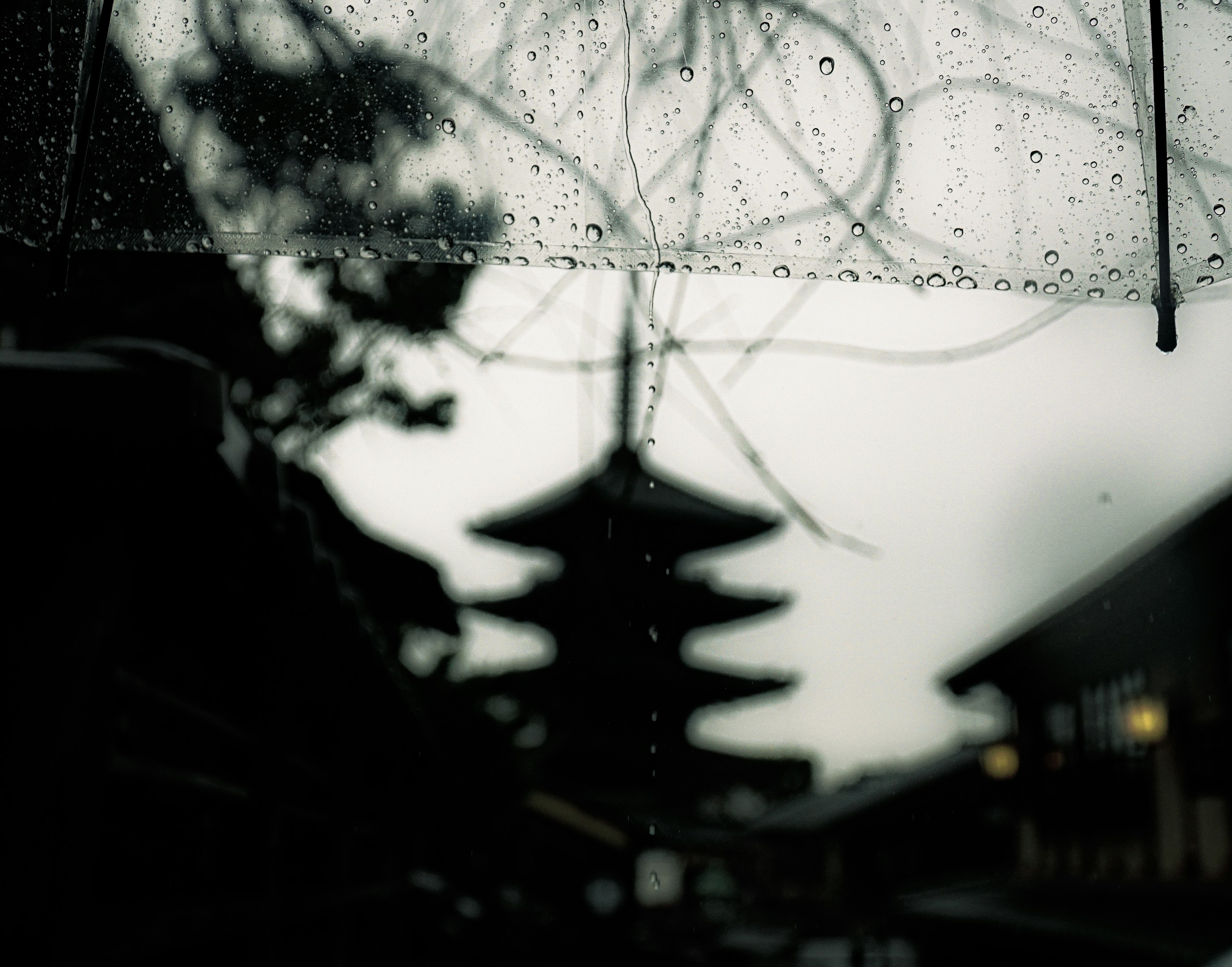 Blick auf eine alte japanische Pagode durch einen regennassen Schirm mit nebligem Hintergrund