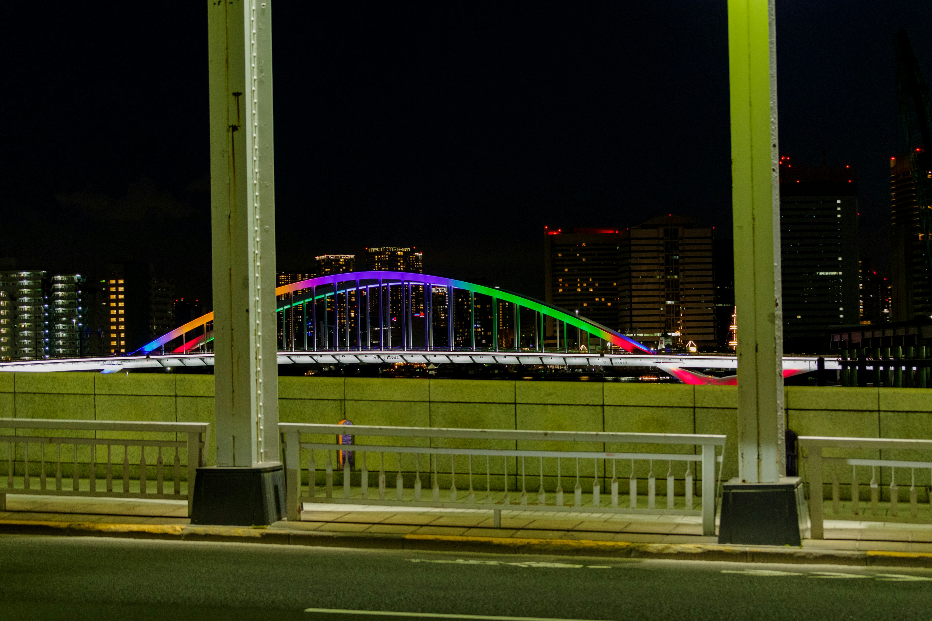 Colorful lights illuminating a bridge at night with city skyline